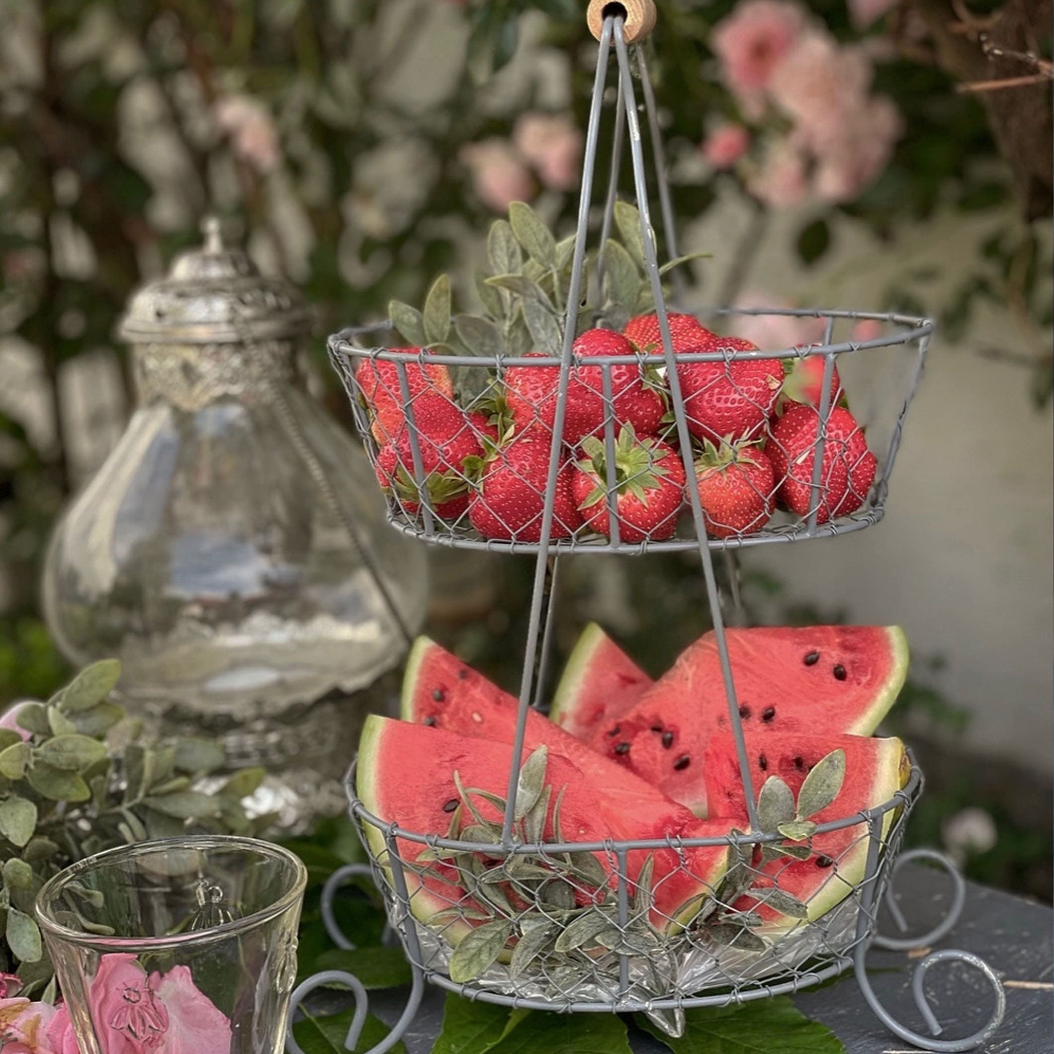 Panier métallique à deux niveaux avec fraises et tranches de pastèque pour une table d'été
