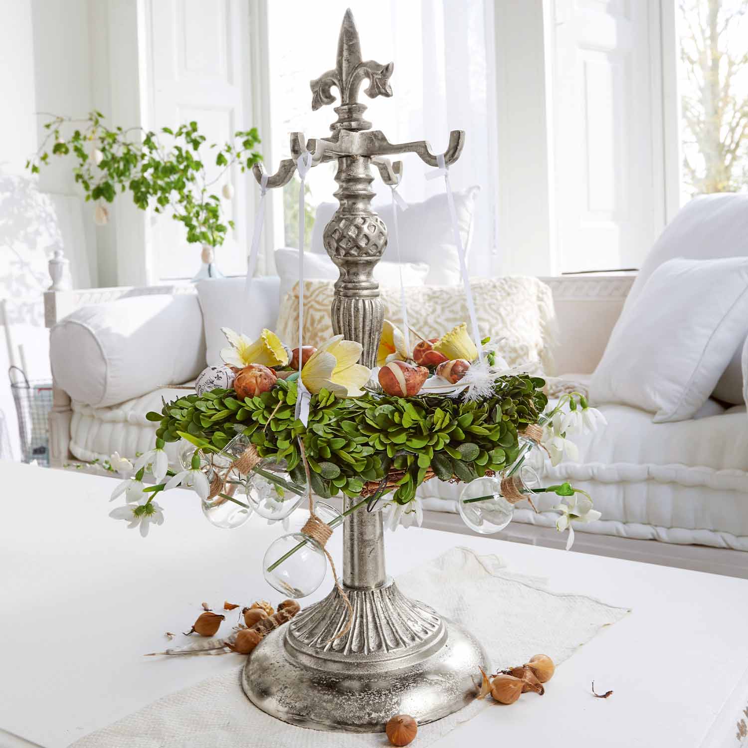 Décoration de table en métal avec couronne verte et boules en verre sur table blanche dans un salon lumineux