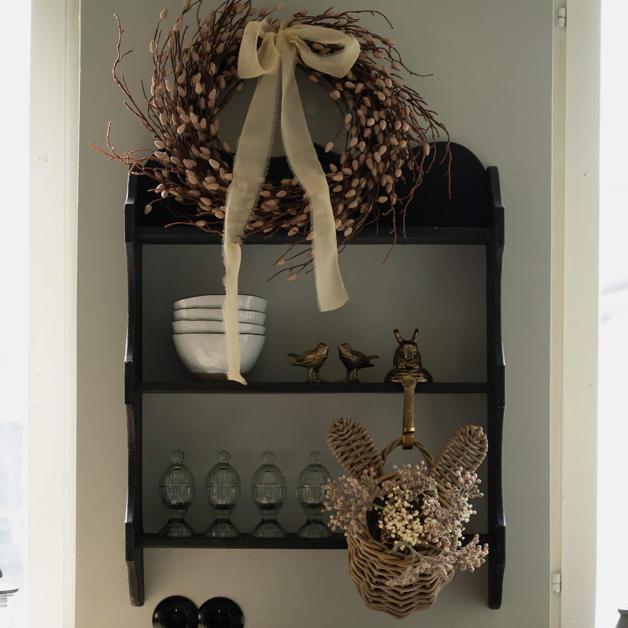 Étagère murale noire en bois avec couronne décorative et panier en osier avec fleurs séchées