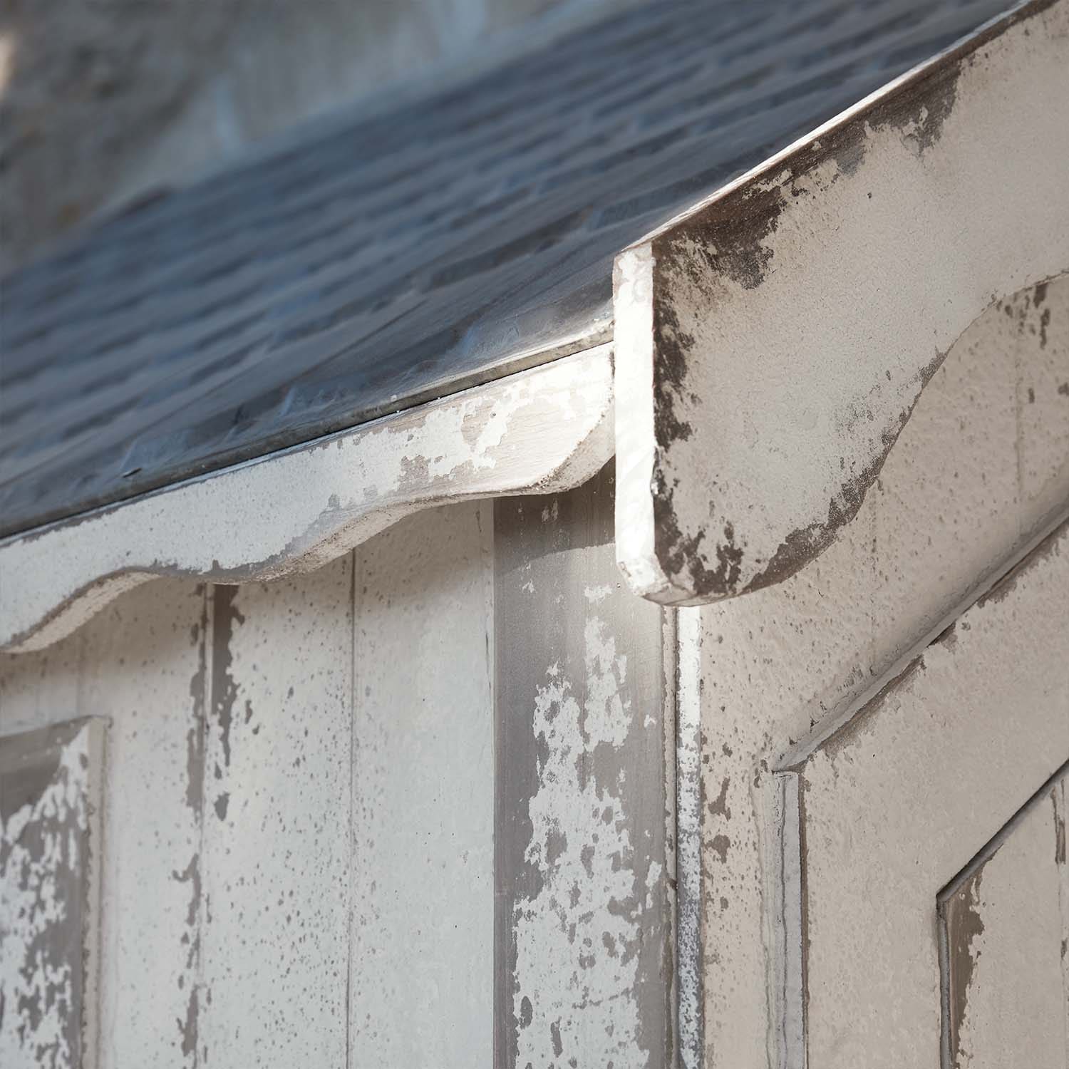 Gros plan sur une structure en bois blanc vieilli avec un toit en métal et une finition incurvée