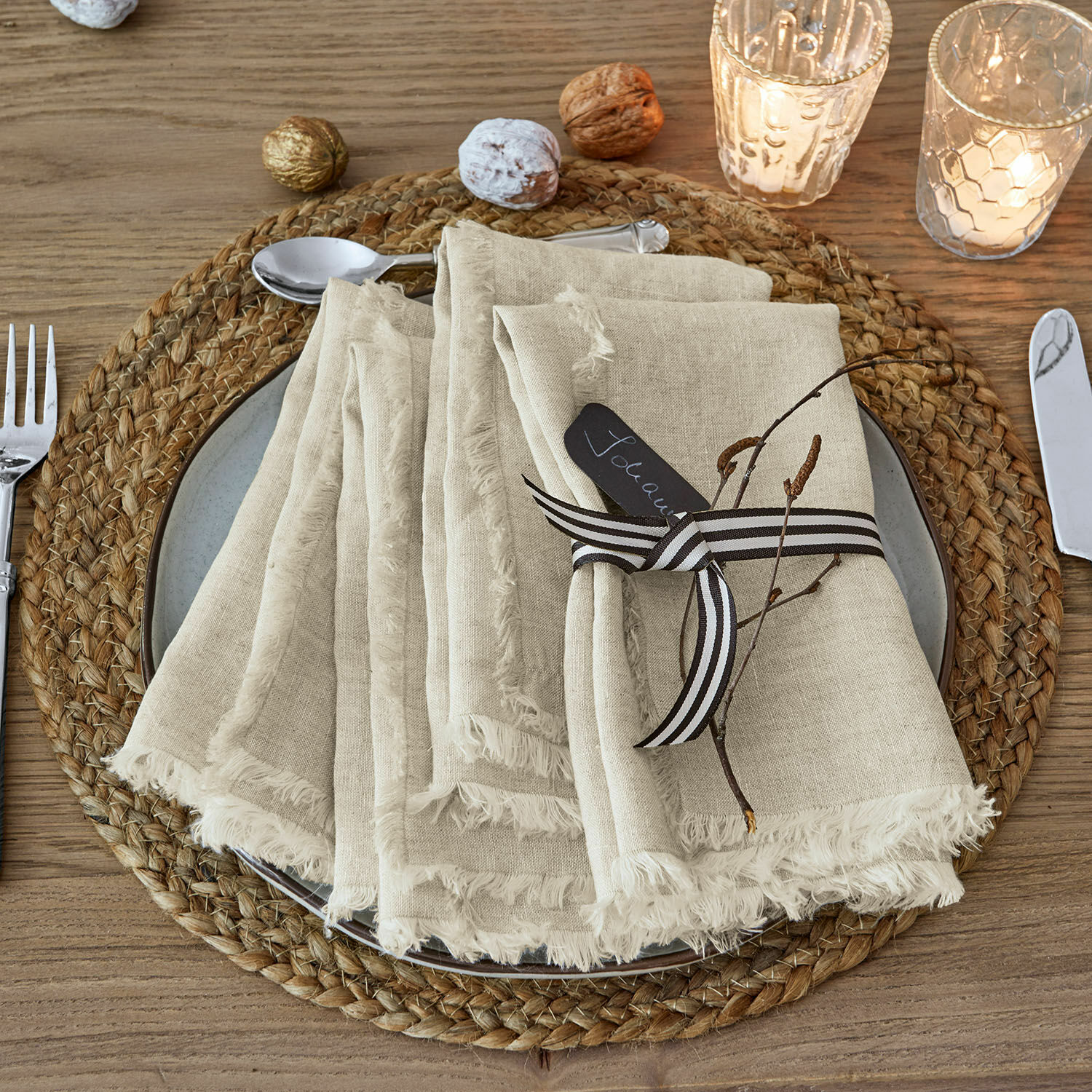 Lot de 4 serviettes de table Largo Serviettes en lin beige à franges sur un dessous de table tressé en bois avec décoration de Noël