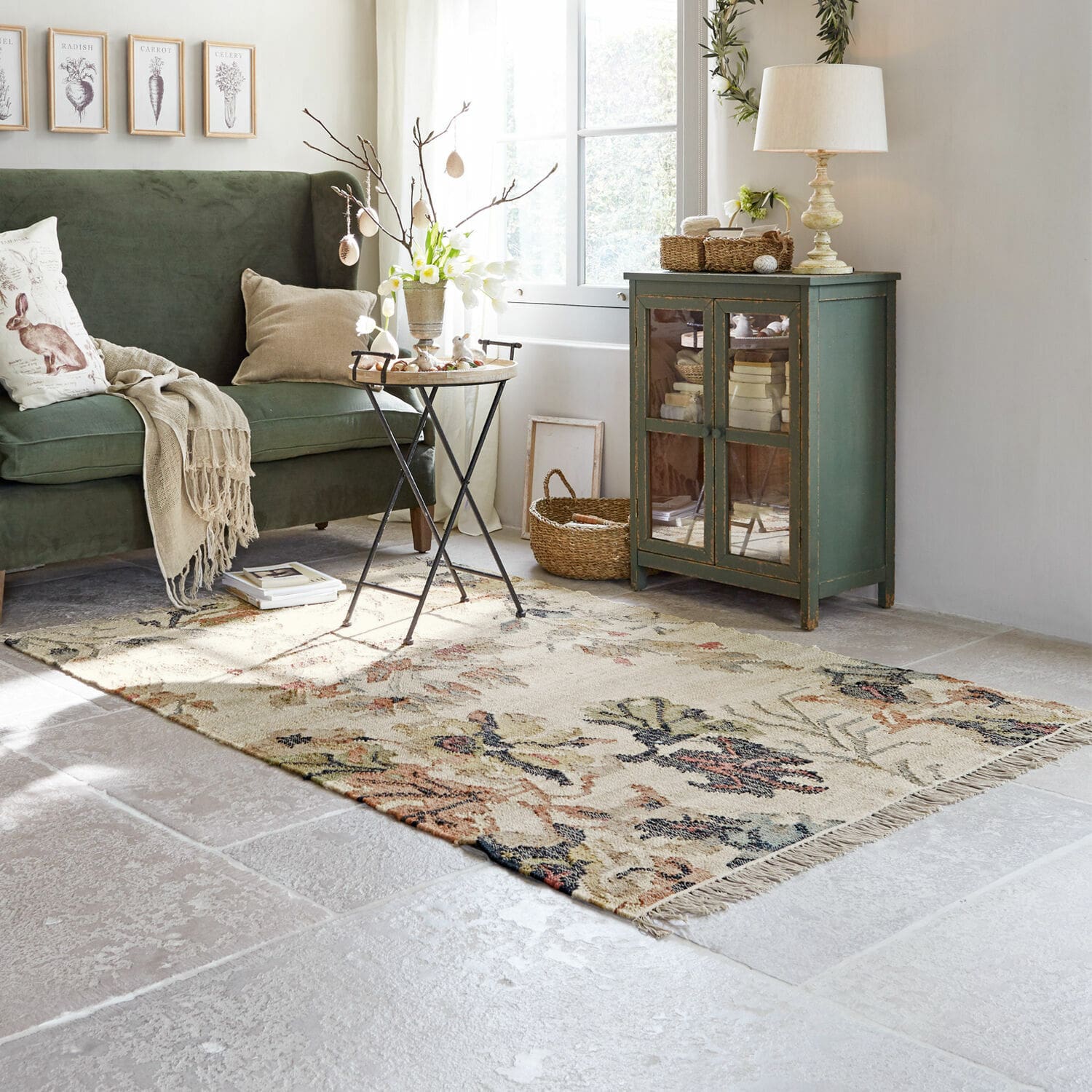 Tapis Osorno Salon chaleureux avec canapé vert, meuble en bois et tapis floral sur sol clair, décoration cosy