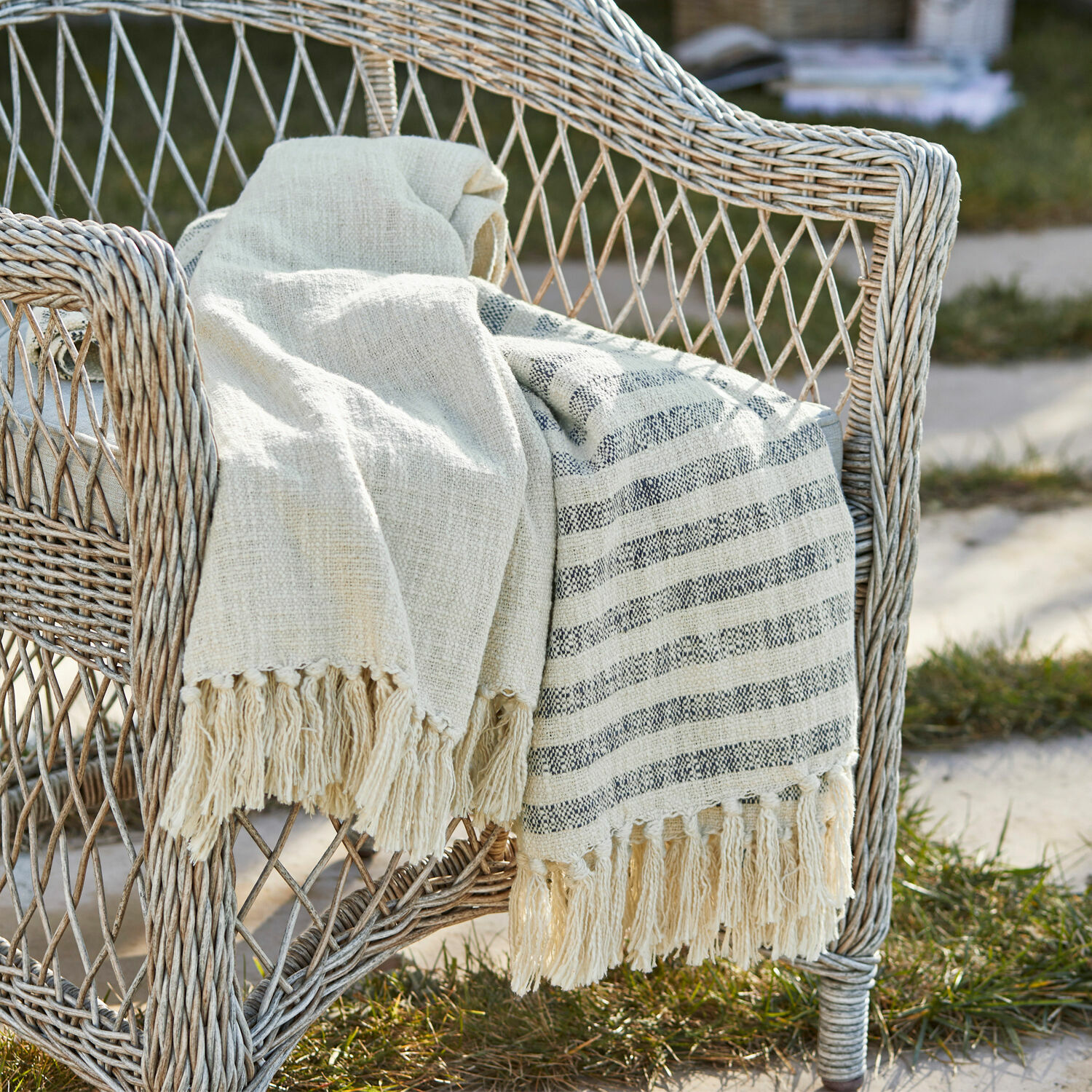 Plaid Marpent Plaid beige en coton avec franges sur fauteuil en osier, décoration extérieure confortable