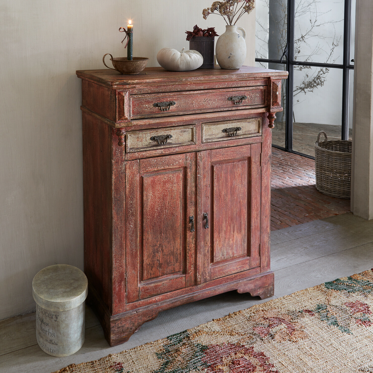 Commode Jolivarne Buffet en bois rustique rouge avec poignées décoratives et objets décoratifs sur le dessus