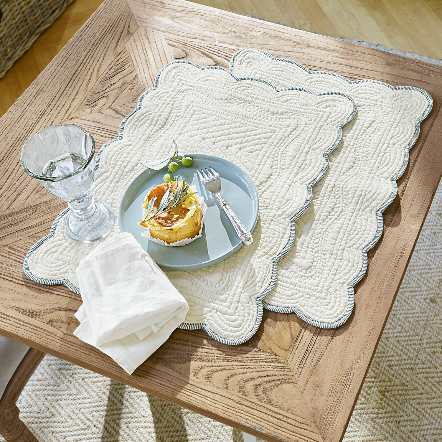 Lot de 2 sets de table Fontienne Sets de table matelassés en coton beige avec bord bleu sur table en bois avec dessert et verre