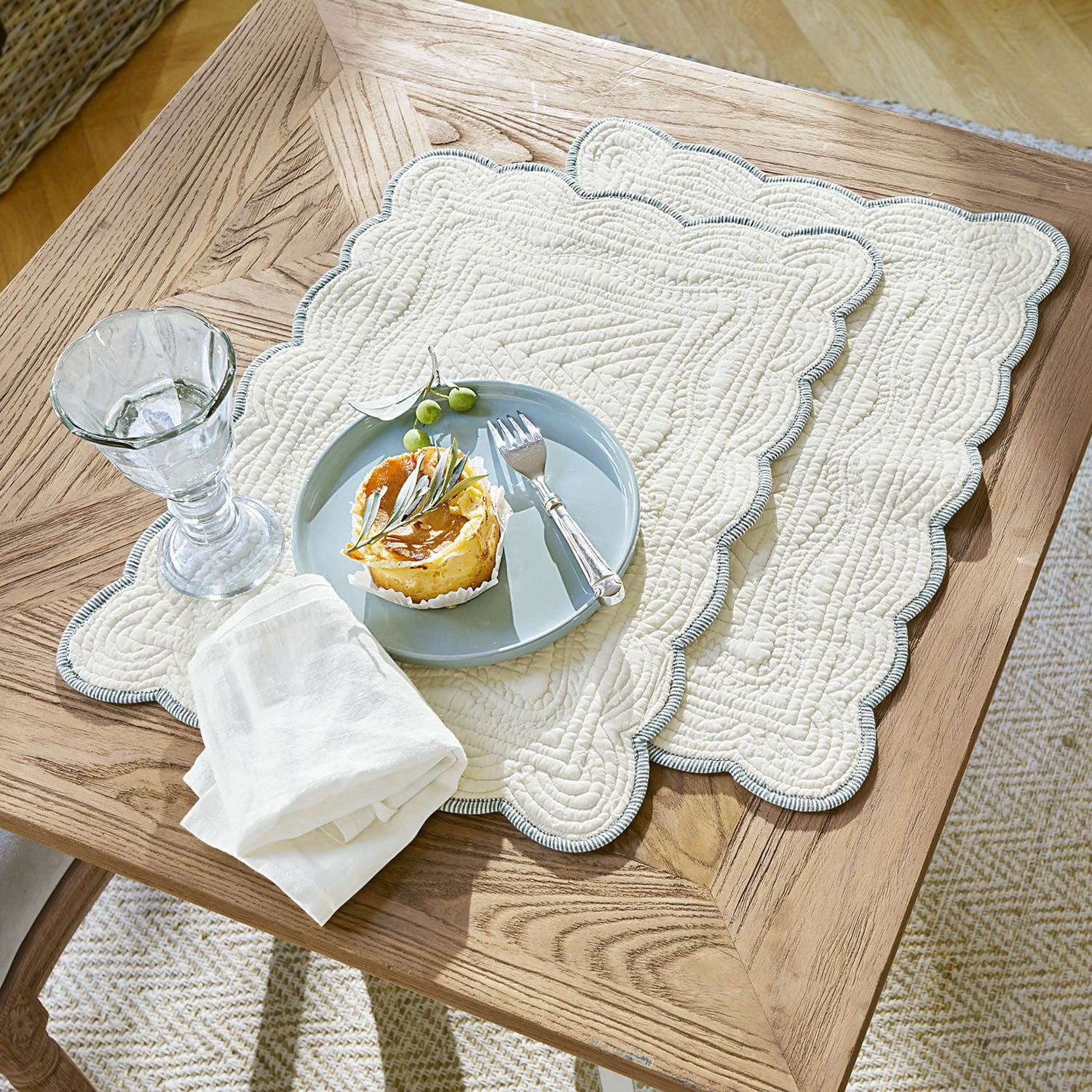 Lot de 2 sets de table Fontienne Sets de table matelassés en coton beige avec bord bleu sur table en bois avec dessert et verre