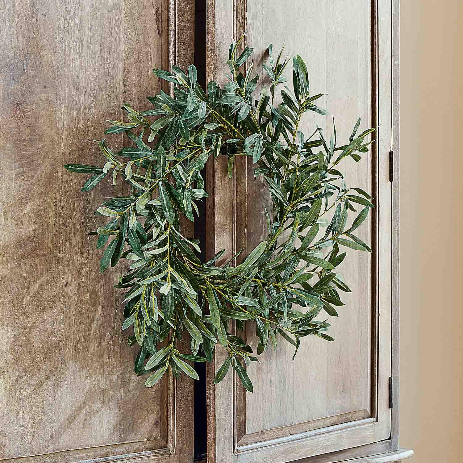 Couronne décorative en feuilles vertes suspendue sur une porte en bois, décoration naturelle d'intérieur