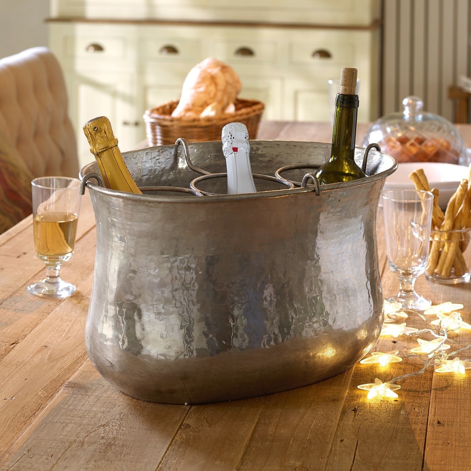 Seau à champagne Montgomery Grand seau en métal martelé avec poignées et compartiments pour trois bouteilles sur table en bois
