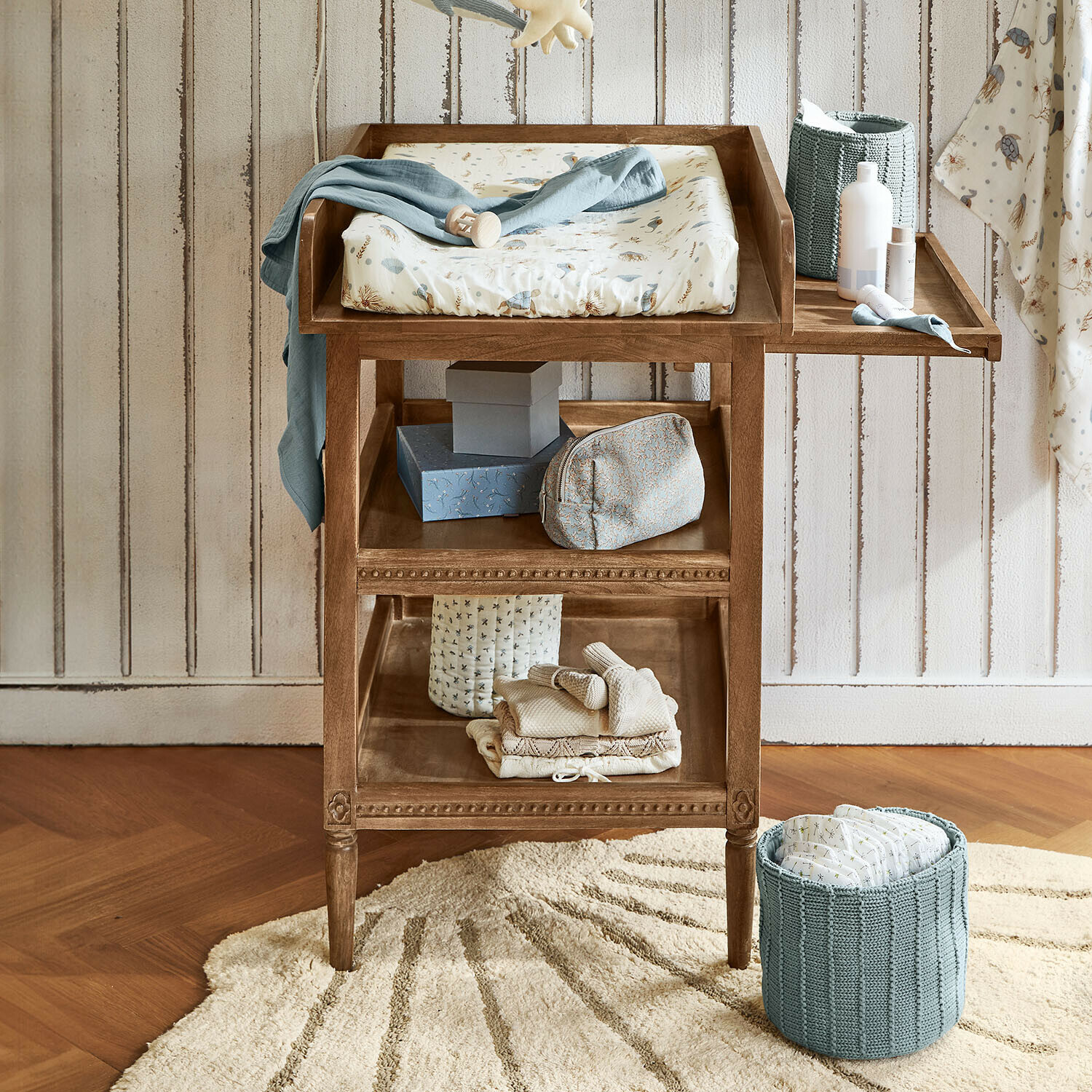 Console à langer Bellouvre Table à langer en bois avec matelas doux beige et bleu, étagères pour accessoires dans une chambre d'enfant