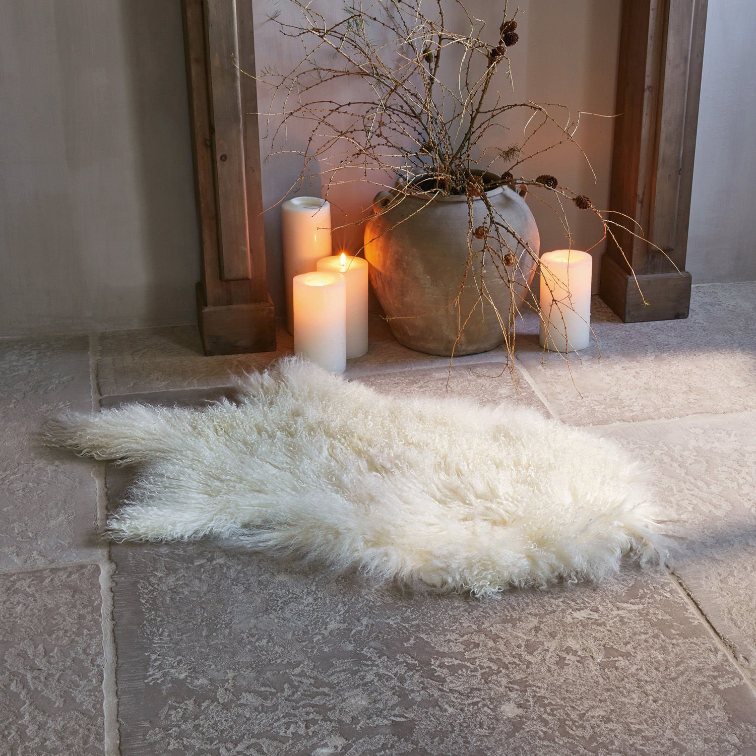 Peau d'agneau Gad Tapis doux blanc en peau de mouton sur sol en pierre avec bougies et vase en argile