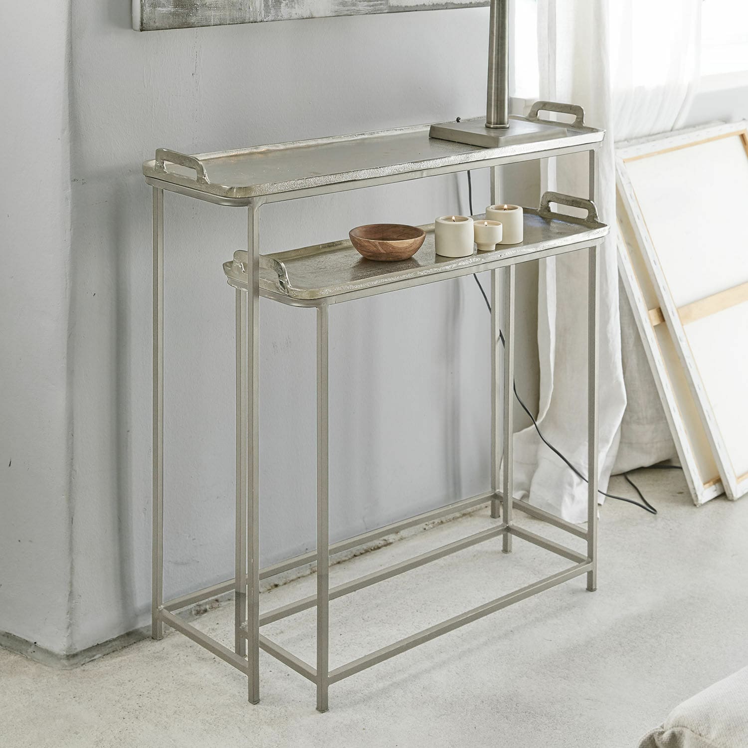 Ensemble de deux tables d'appoint en métal argenté avec plateaux et décorations dans un intérieur moderne