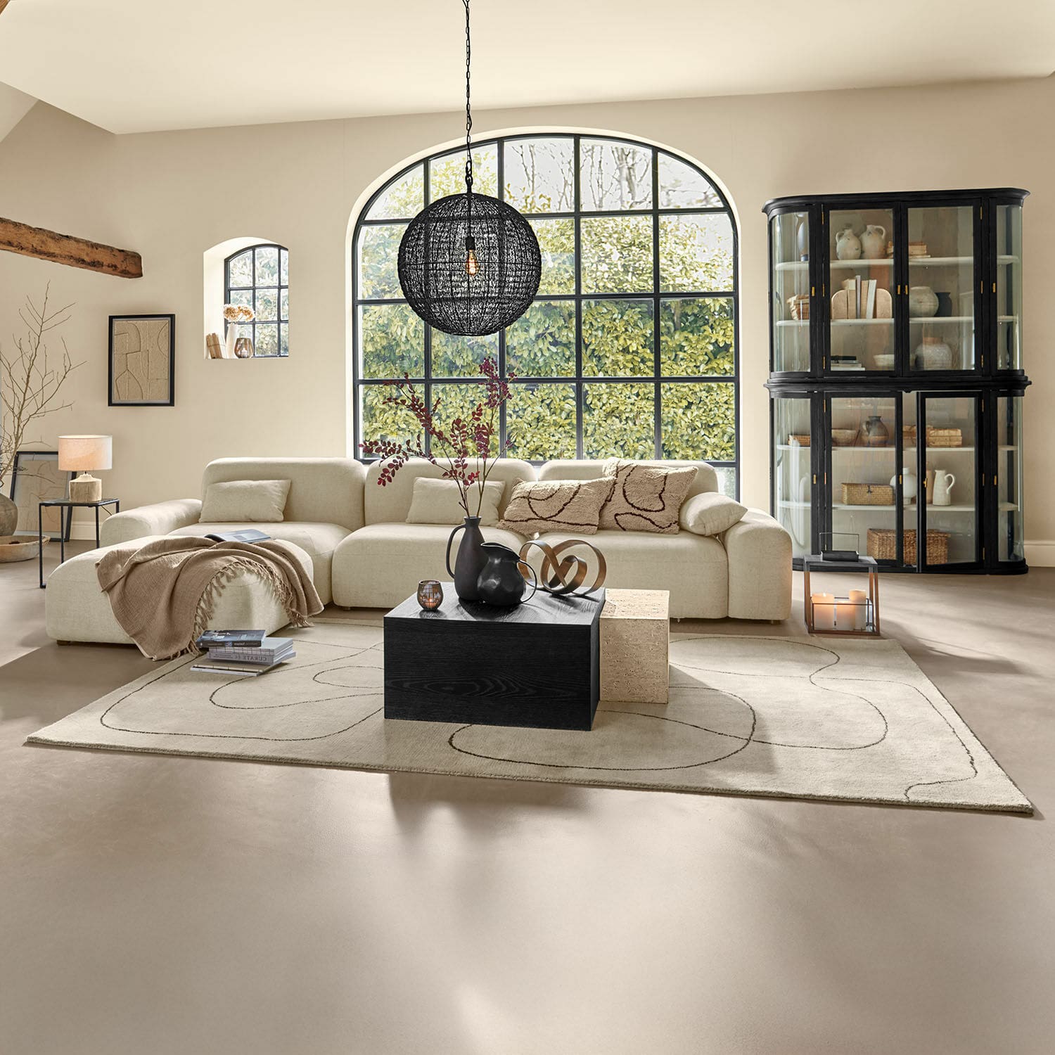 Tapis Lavinois Salon spacieux avec canapé beige en tissu et table basse noire en bois sur tapis à motif