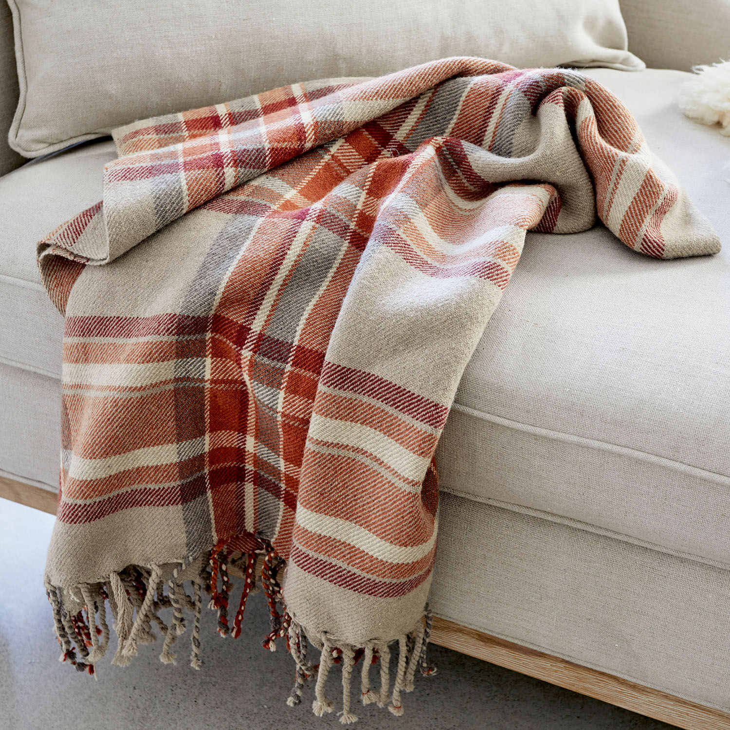 Plaid Tartan Plaid en coton à carreaux beige et rouge posé sur un canapé clair, accessoire déco confortable