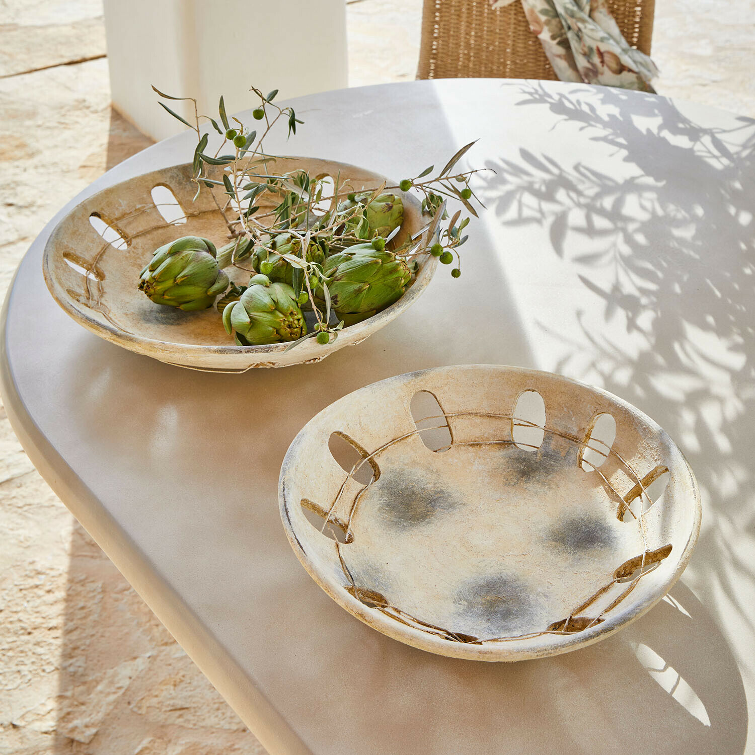 Lot de 2 coupes décoratives Delunas Deux bols décoratifs en céramique beige sur une table, l'un contenant des artichauts verts
