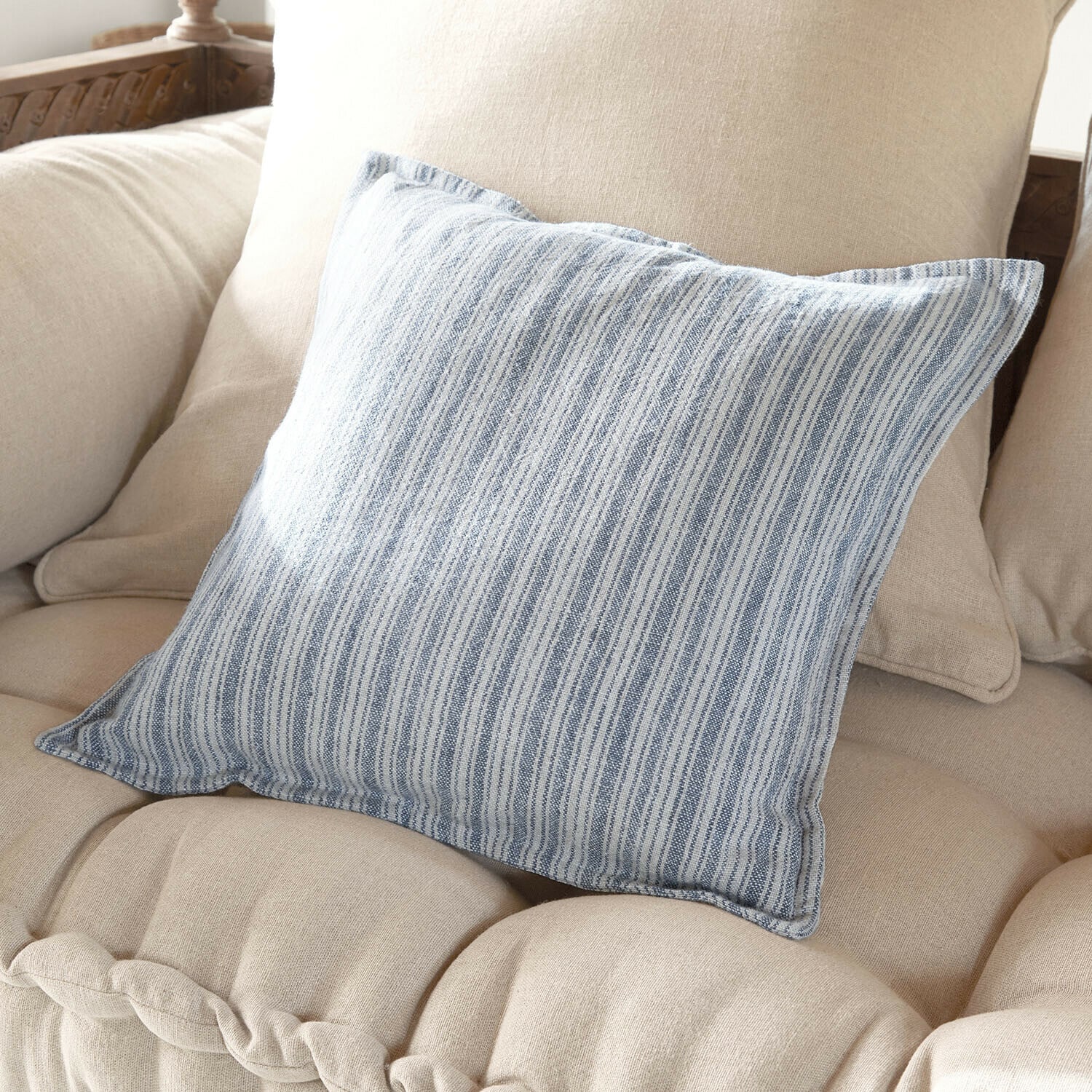 Housse de coussin Freydaal Coussin décoratif en coton rayé bleu et blanc sur canapé beige, accessoire tendance pour salon