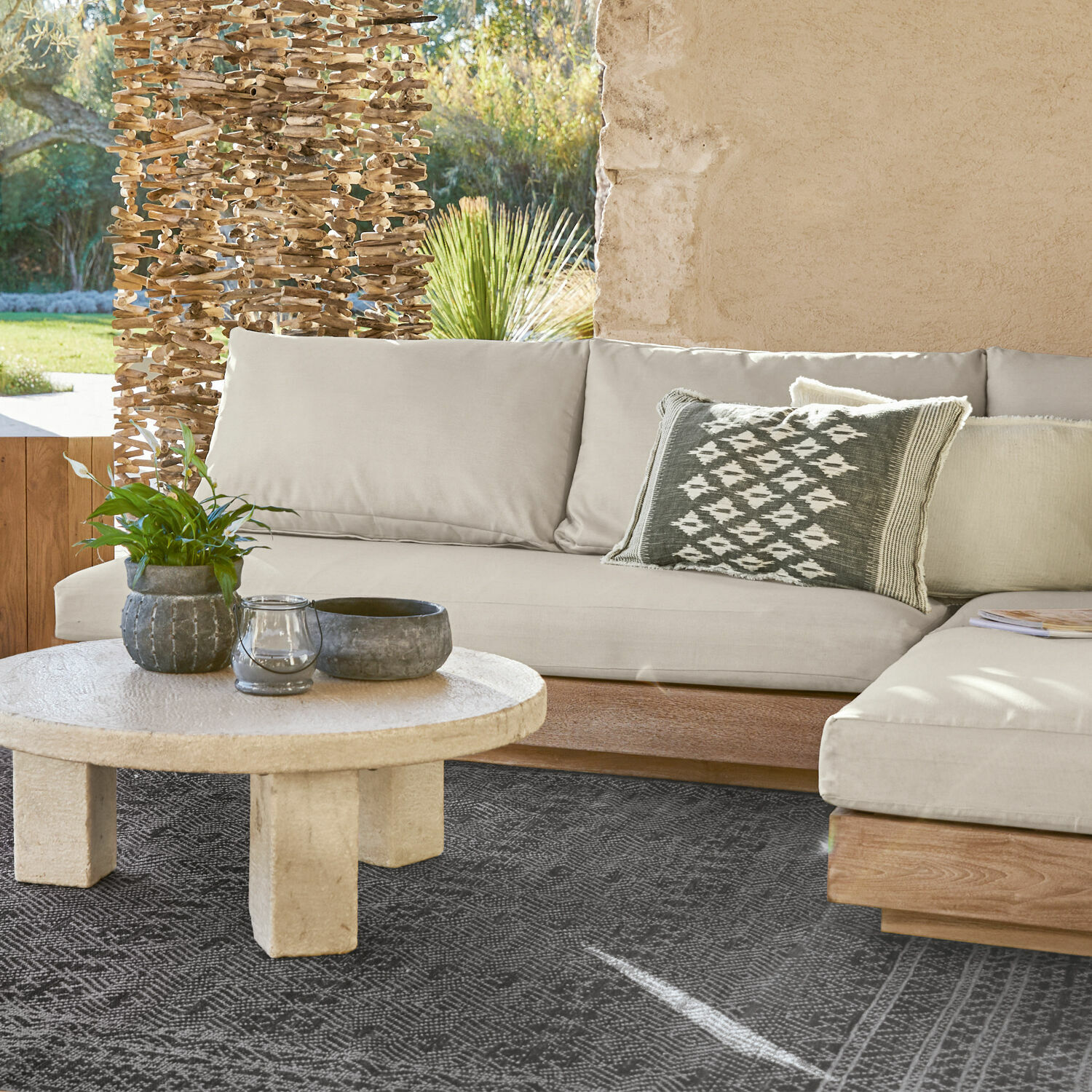 Élément de canapé Courtelevant Canapé beige avec base en bois et coussin décoratif sur tapis noir dans un salon lumineux.