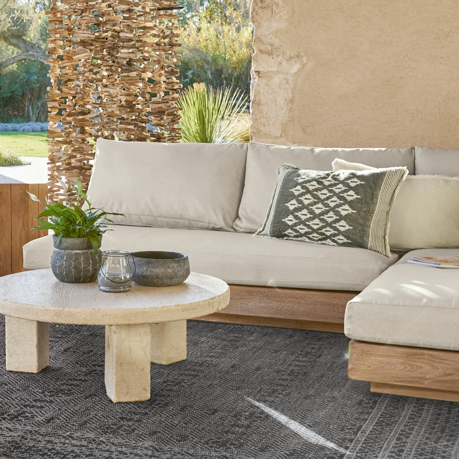 Élément de canapé Courtelevant Canapé beige avec base en bois et coussin décoratif sur tapis noir dans un salon lumineux.