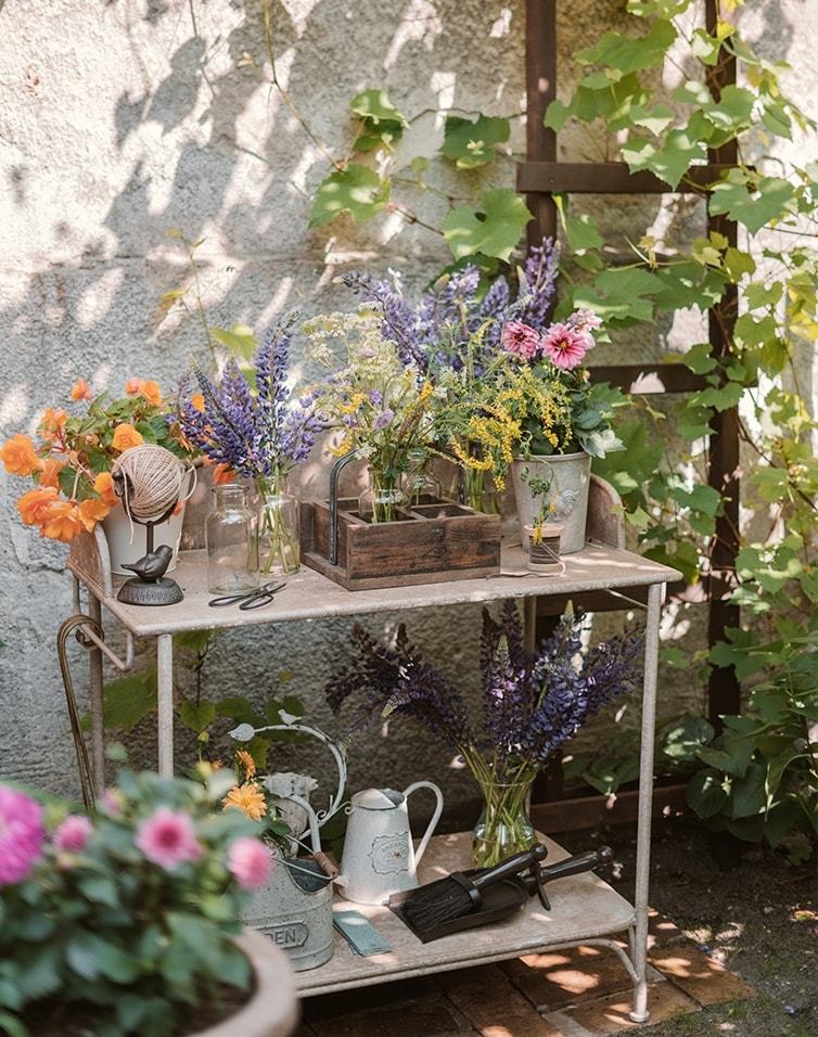 Table de jardin en métal avec fleurs et outils de jardinage dans un coin ombragé ensoleillé