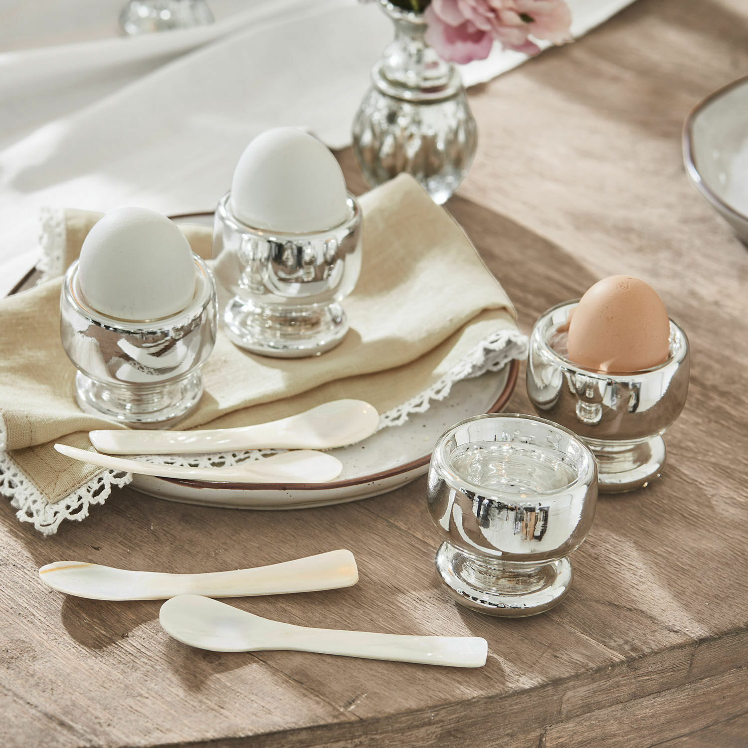 Lot de 4 coquetiers Lilligret Ensemble de porte-œufs en métal argenté avec œufs blancs et bruns et petites cuillères blanches sur table en bois