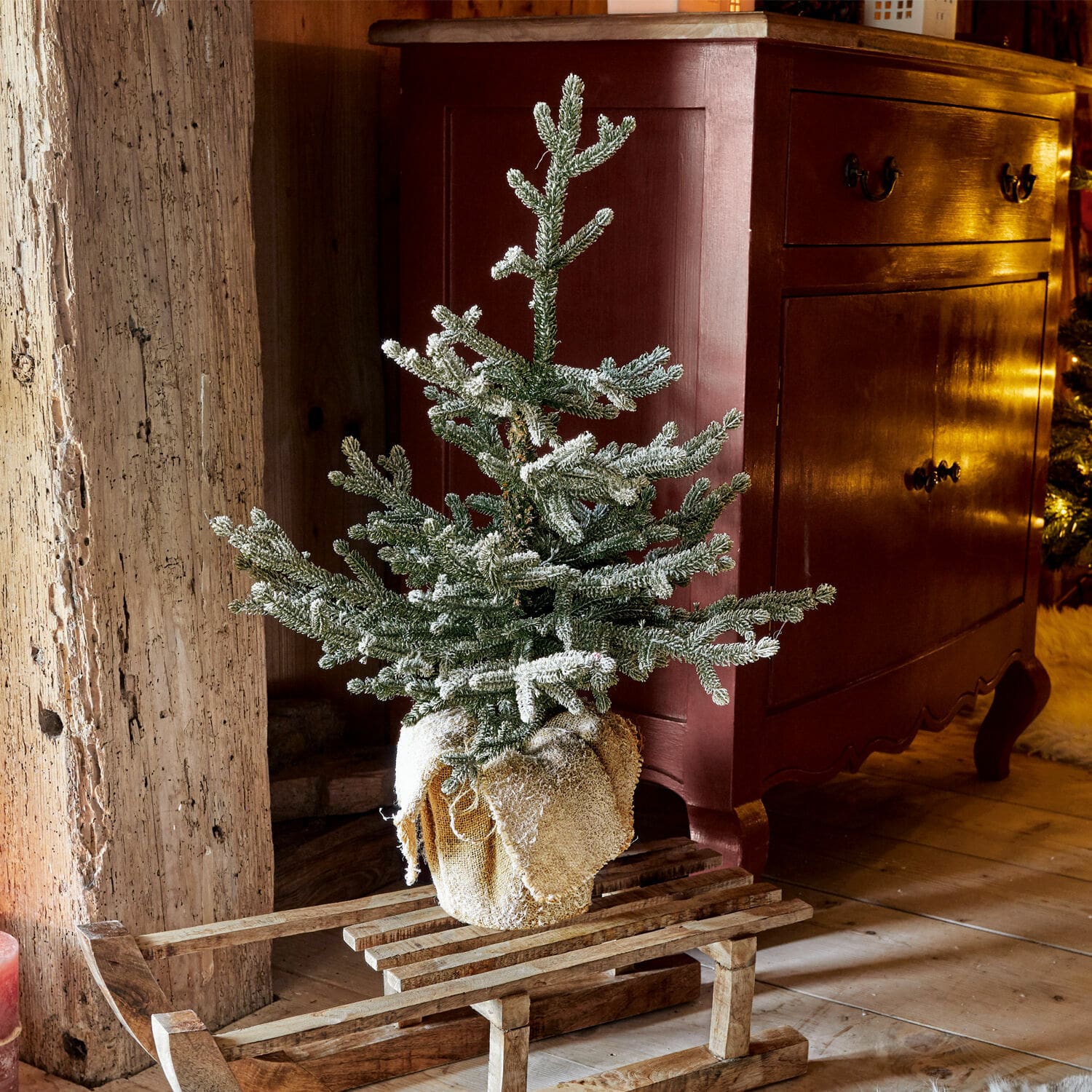 Sapin décoratif Glenda Petit sapin artificiel enneigé sur une luge en bois dans un intérieur rustique chaleureux