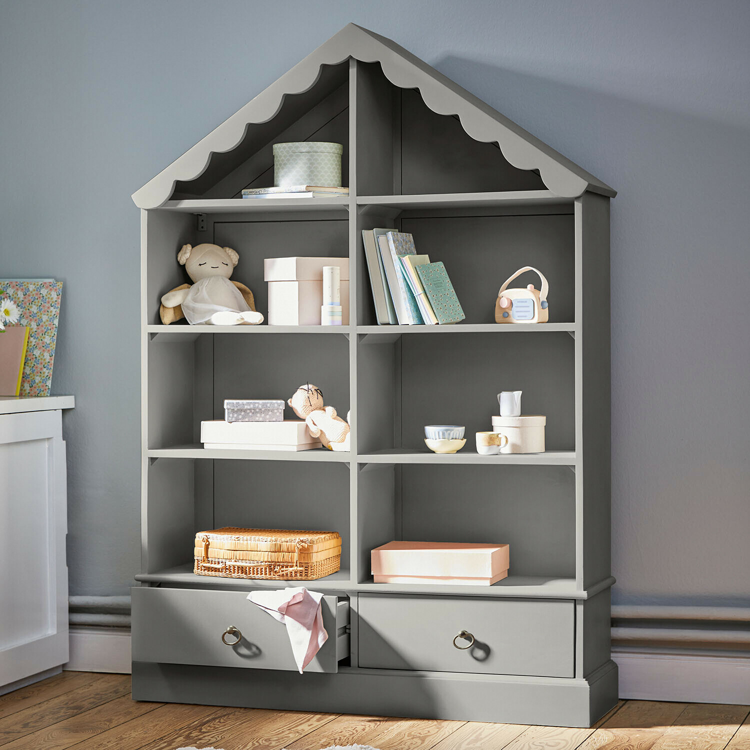 Étagère grise en bois en forme de maison avec jouets et livres pour chambre d'enfant