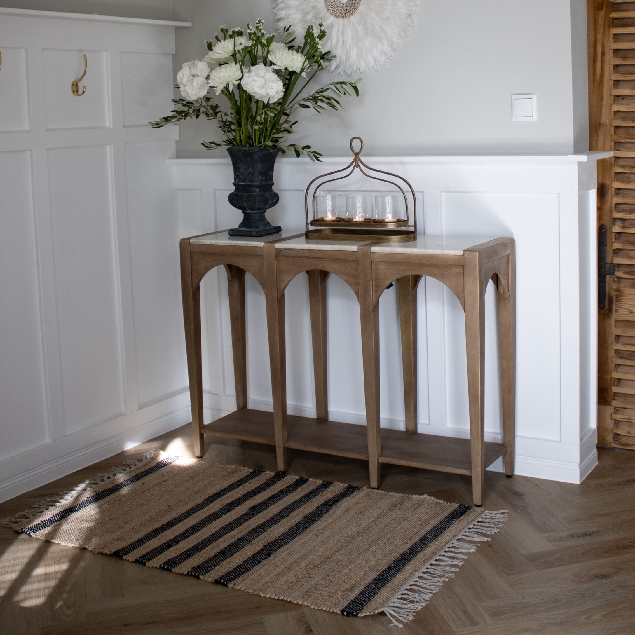 Tapis beige à rayures noires avec franges sur un sol en bois dans un intérieur lumineux