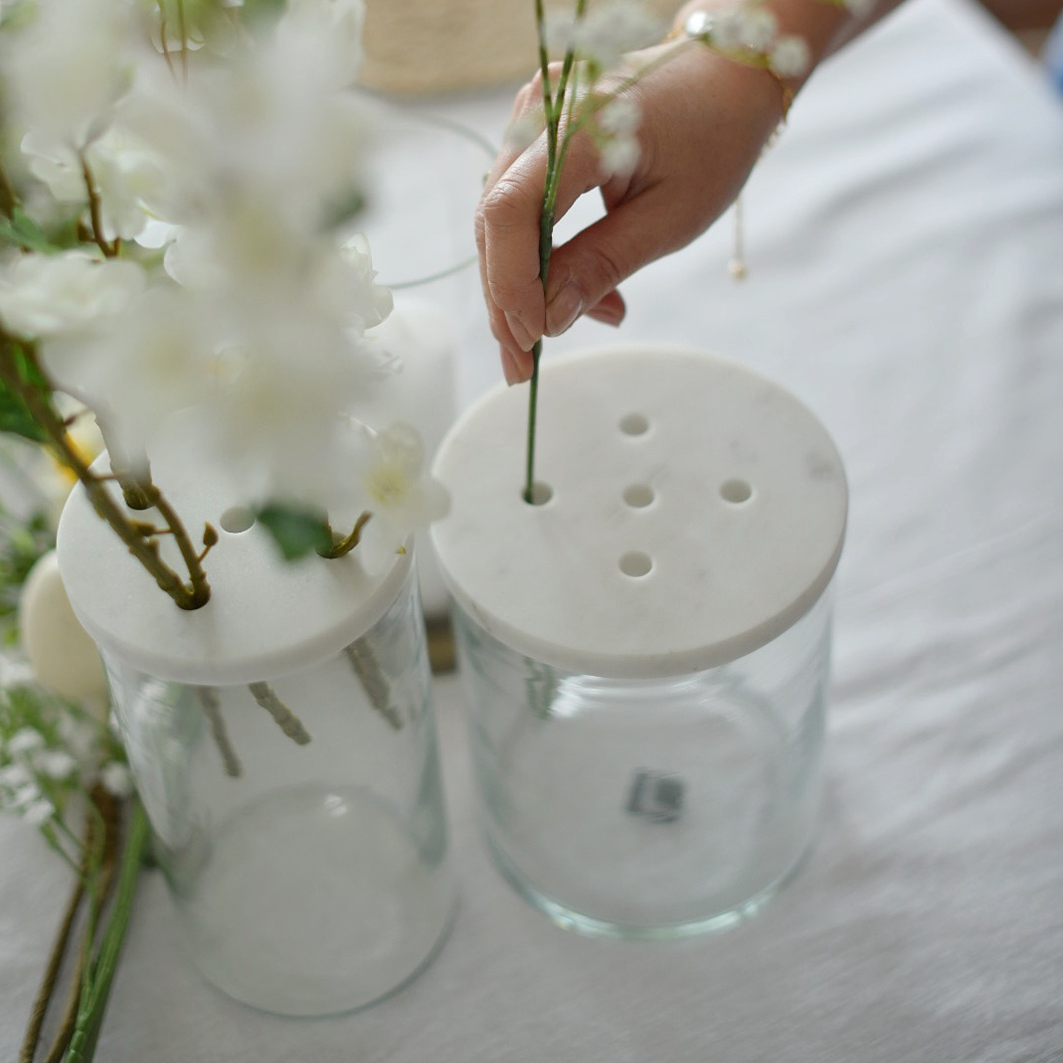 Vase en verre avec couvercle en marbre blanc perforé pour arranger les fleurs sur une table