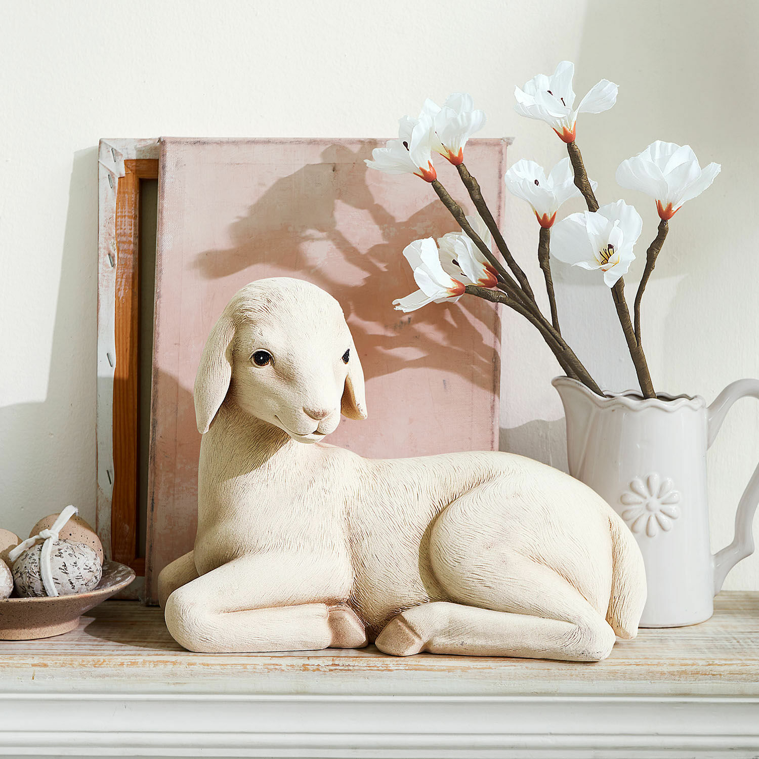 Agneau décoratif Xénandrine Figurine décorative de mouton crème posée sur une étagère en bois avec fleurs et œufs