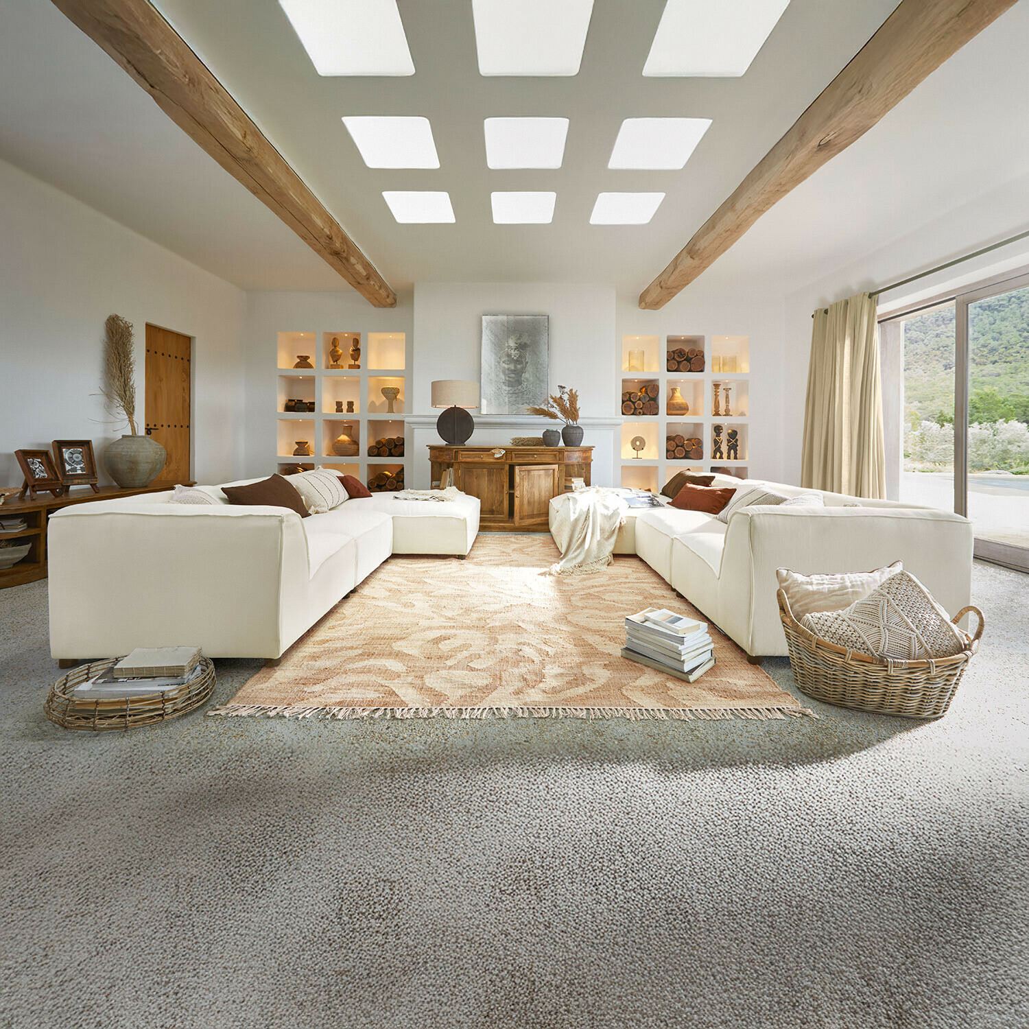 Canapé McLean Salon spacieux avec canapé blanc, poutres en bois, décorations naturelles, tapis beige et grande fenêtre lumineuse