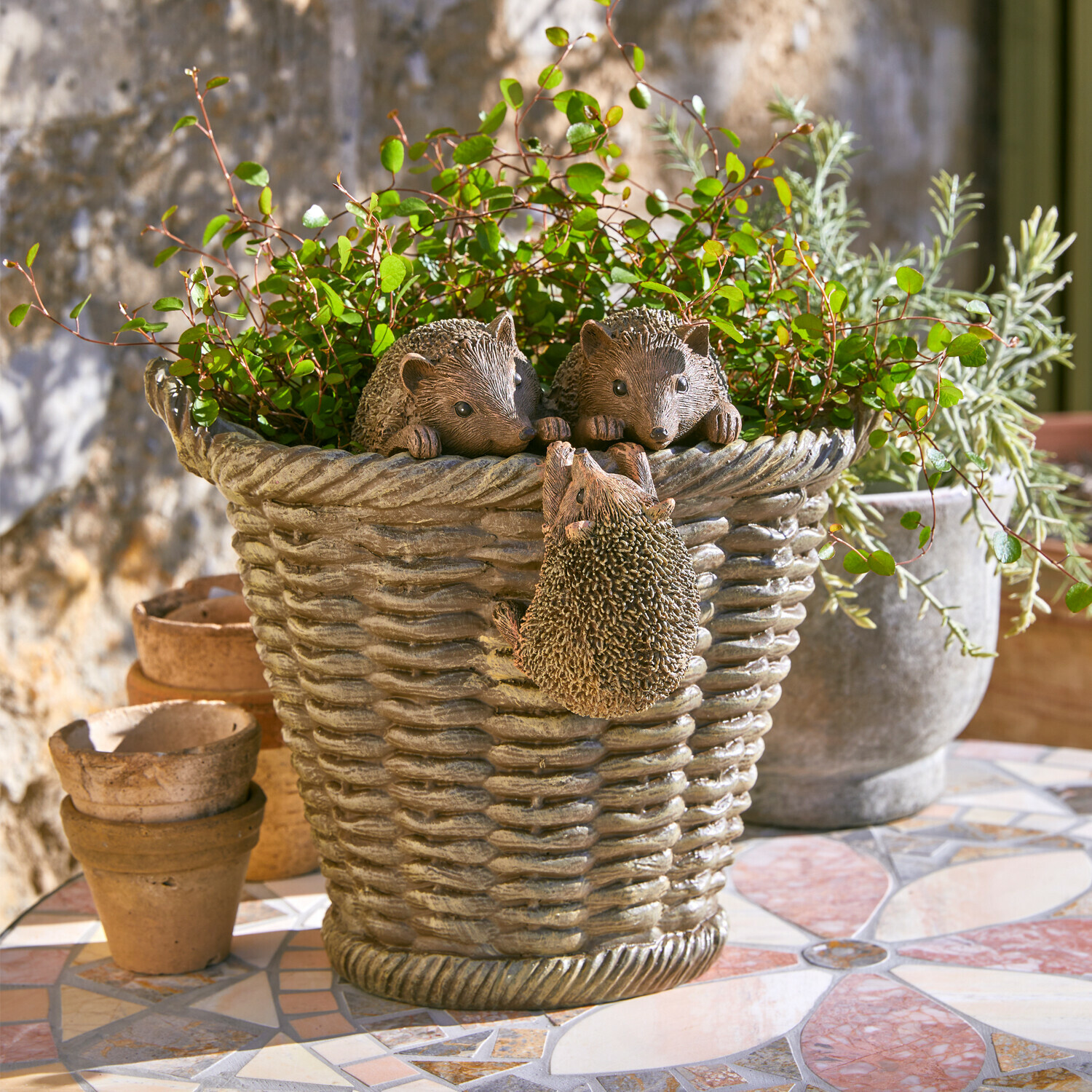Cache-pot Gabriel Jardinière en résine grise avec décoration hérissons et plantes vertes sur terrasse en mosaïque