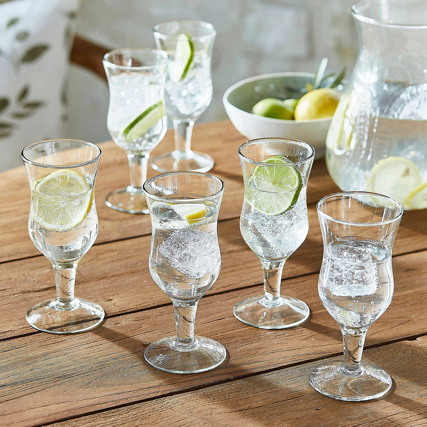 Lot de 6 verres Gaëtane Ensemble de six verres transparents avec eau, glaçons et tranches de citron sur table en bois
