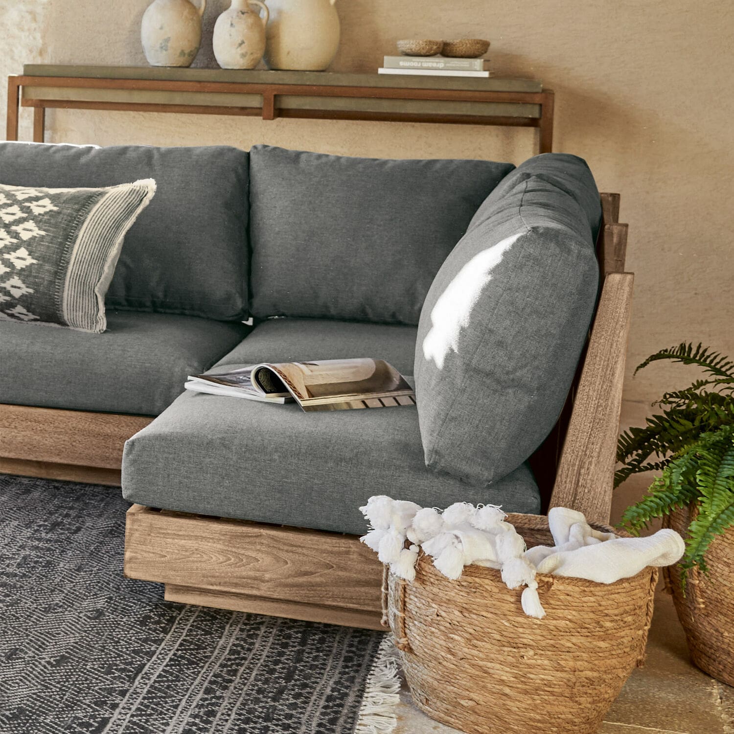 Élément de canapé Courtelevant Canapé gris avec cadre en bois et coussins moelleux dans un salon moderne avec panier en osier