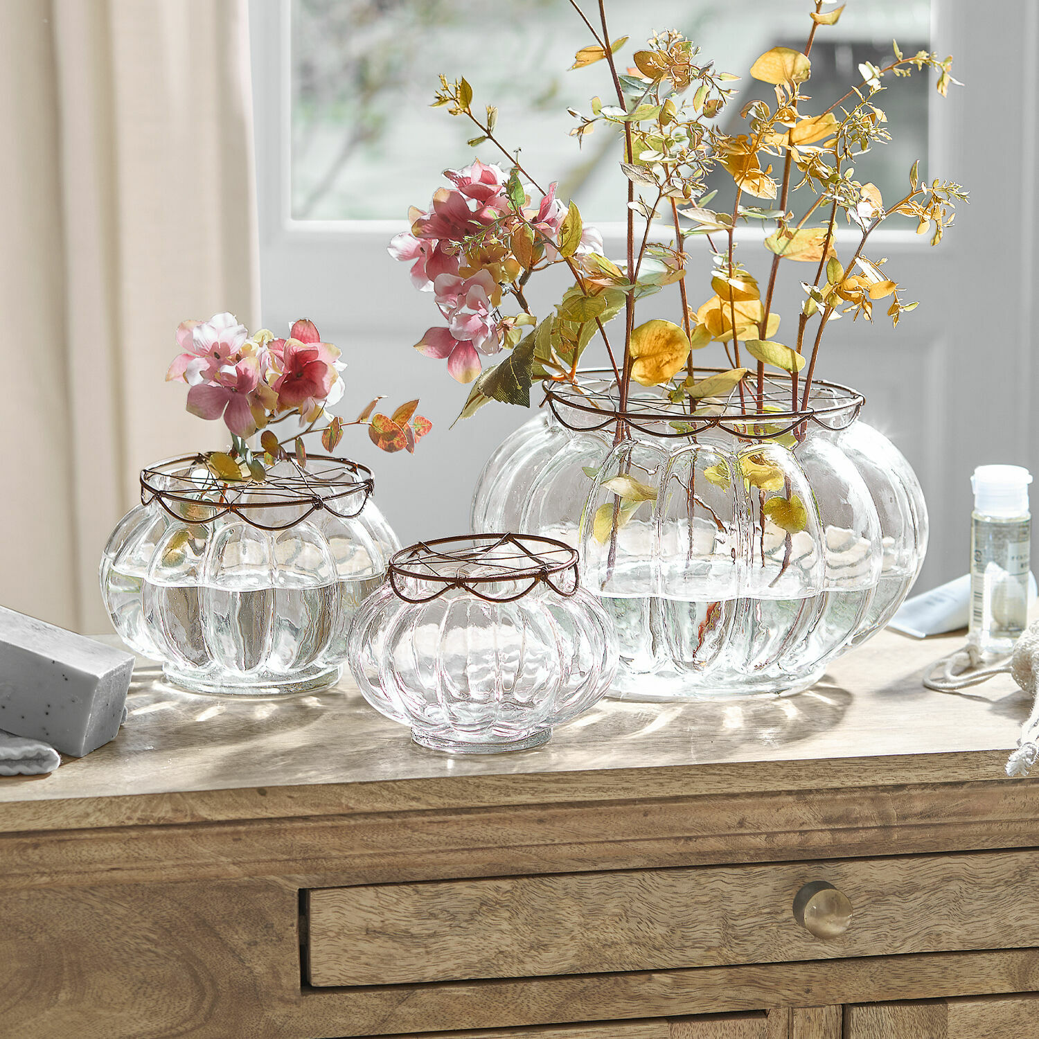 Ensemble de trois vases en verre transparent avec cercles métalliques et fleurs, décoration de table