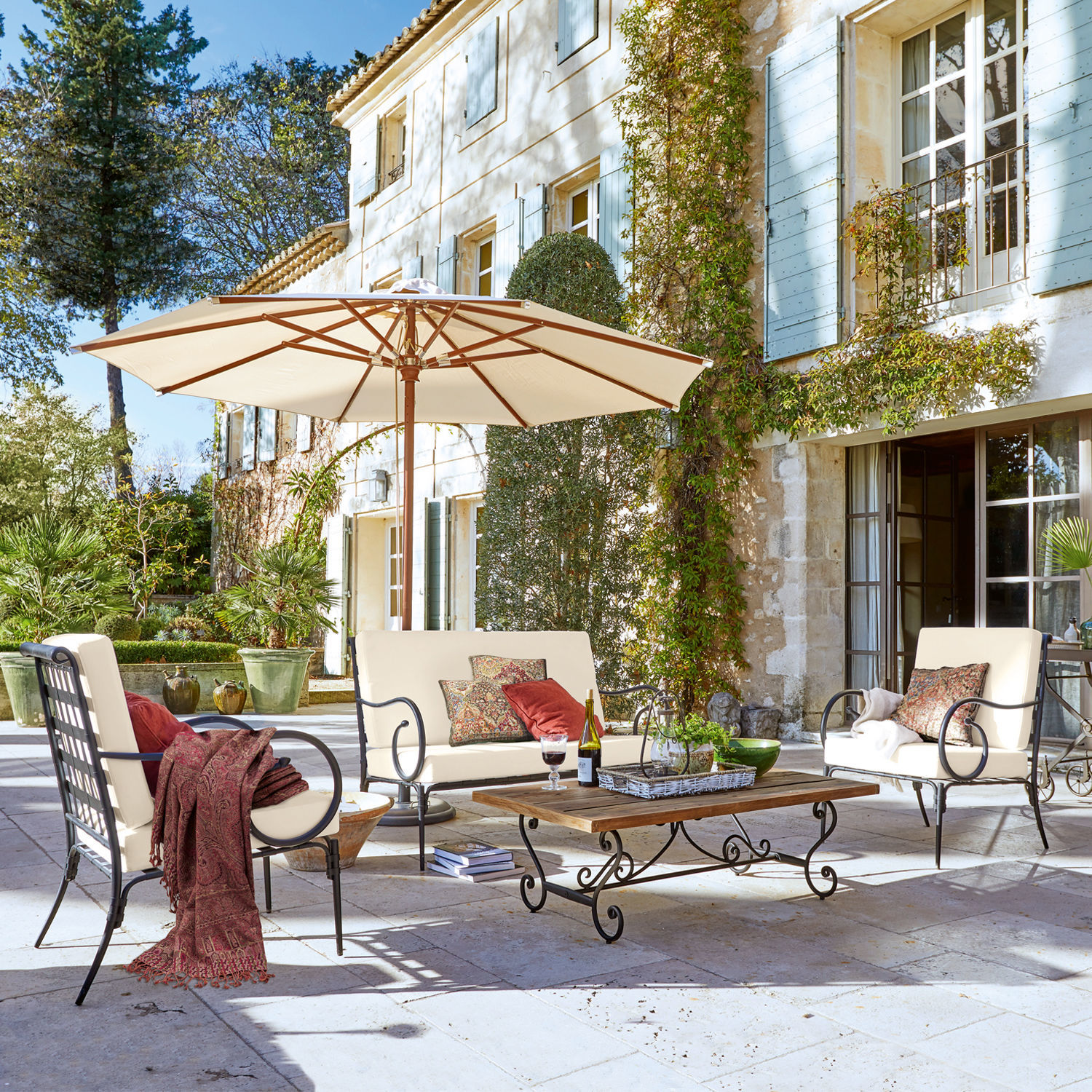 Salon de jardin Massana Ensemble de mobilier de jardin en métal avec coussins crème et parasol sur terrasse en pierre