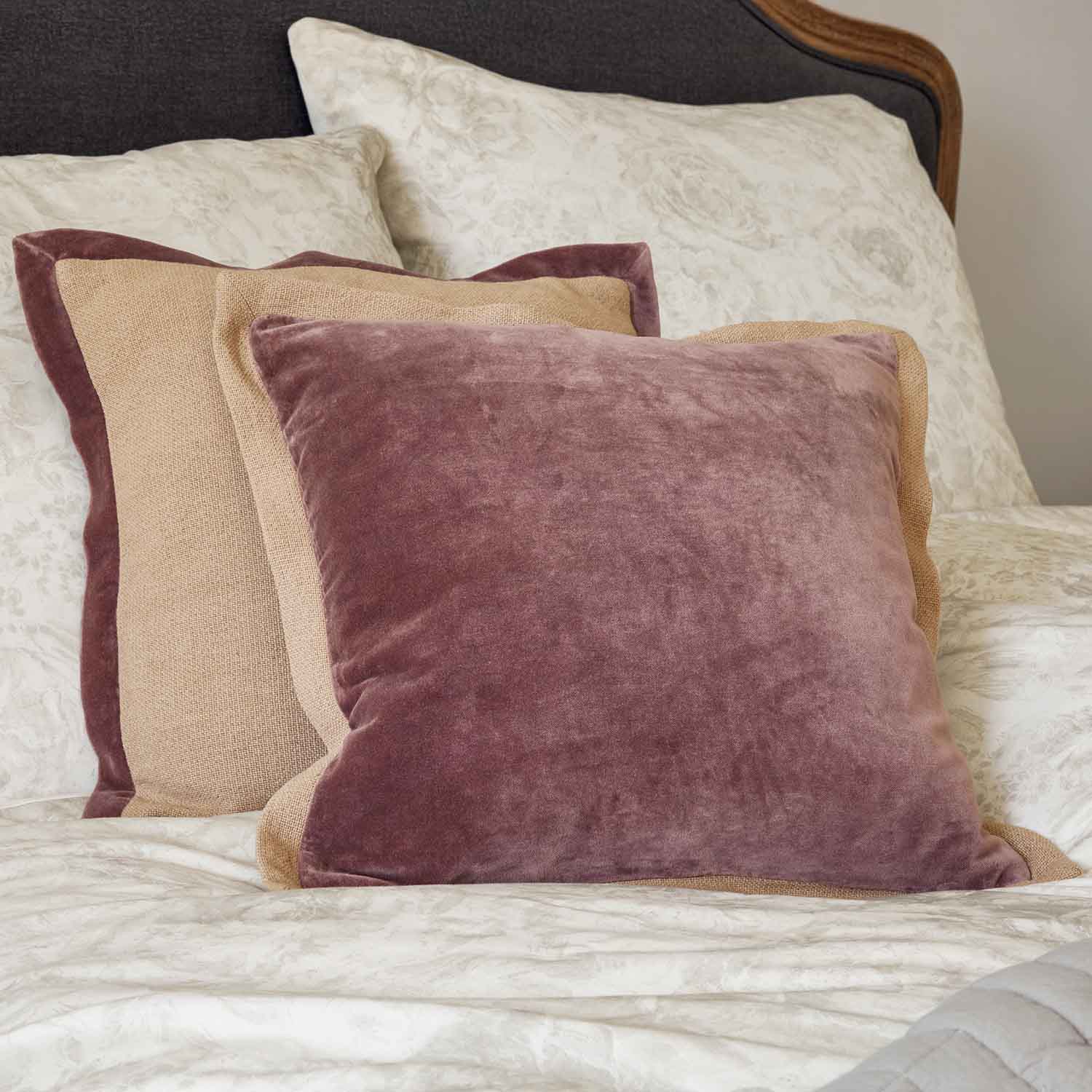 Coussin en lin blanc avec couronne brodée et nœud en velours bordeaux sur fond rouge