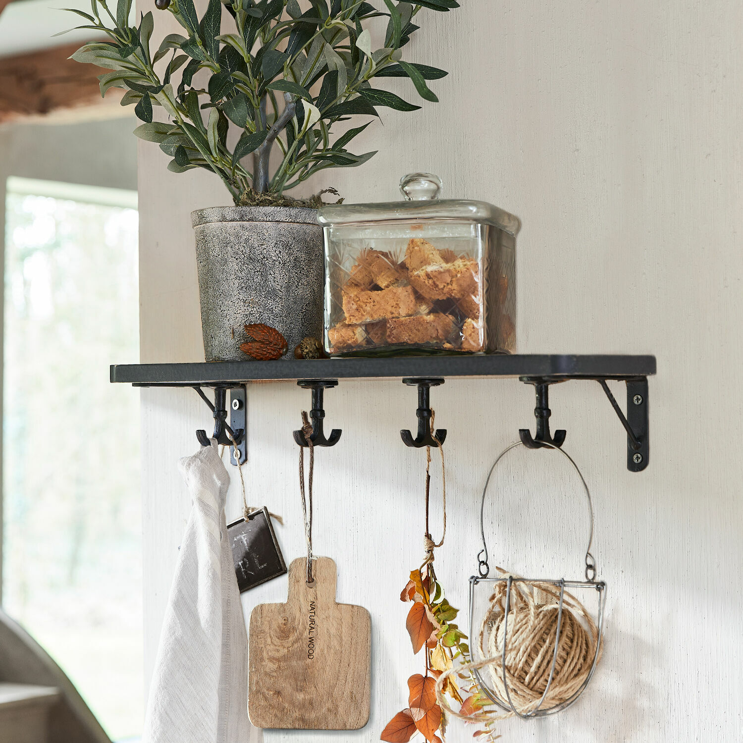 Étagère murale Agnessa Étagère murale noire en métal avec crochets, plante en pot et boîte en verre remplie de biscuits