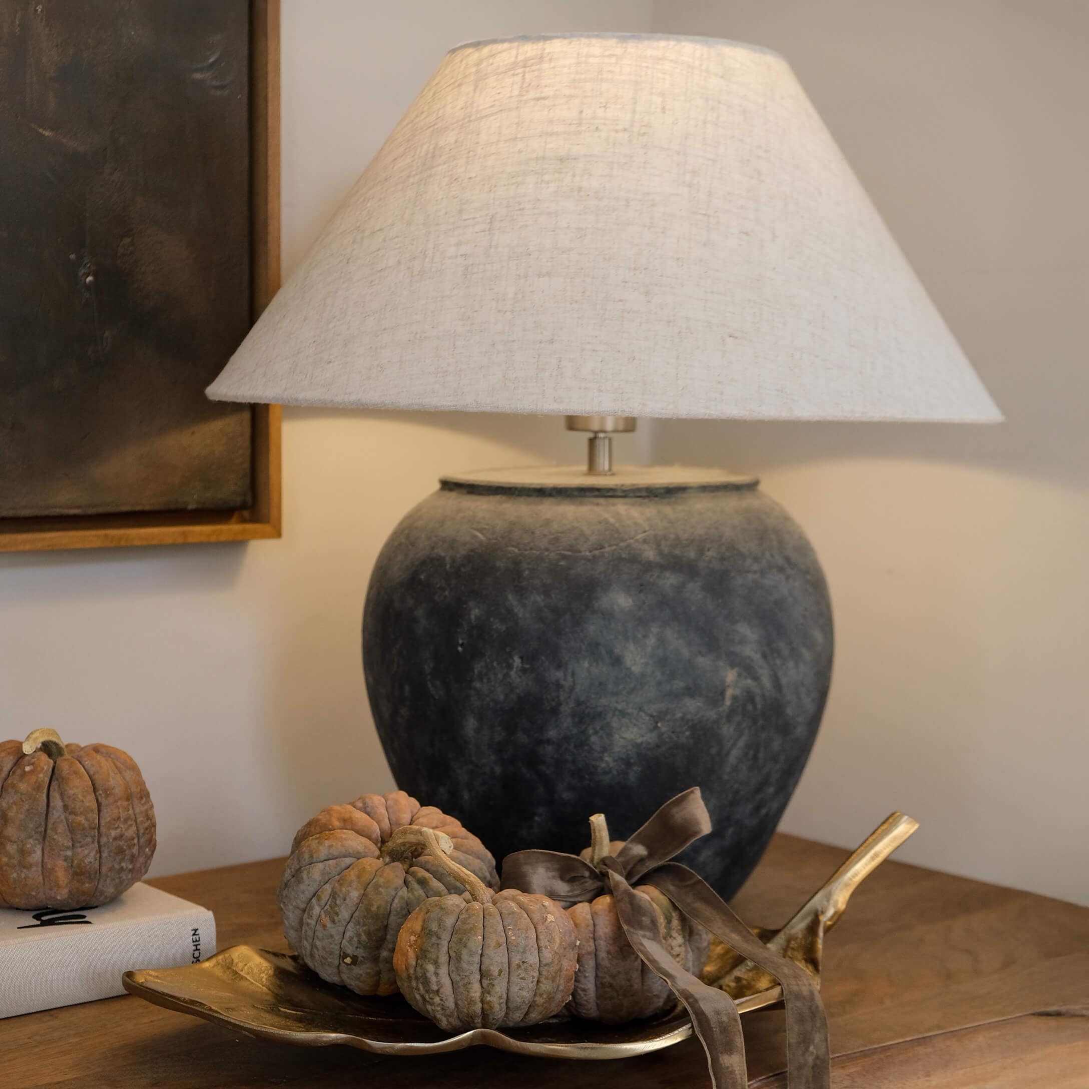 Lampe de table en céramique gris foncé avec abat-jour beige et décoration de petites citrouilles sur plateau doré