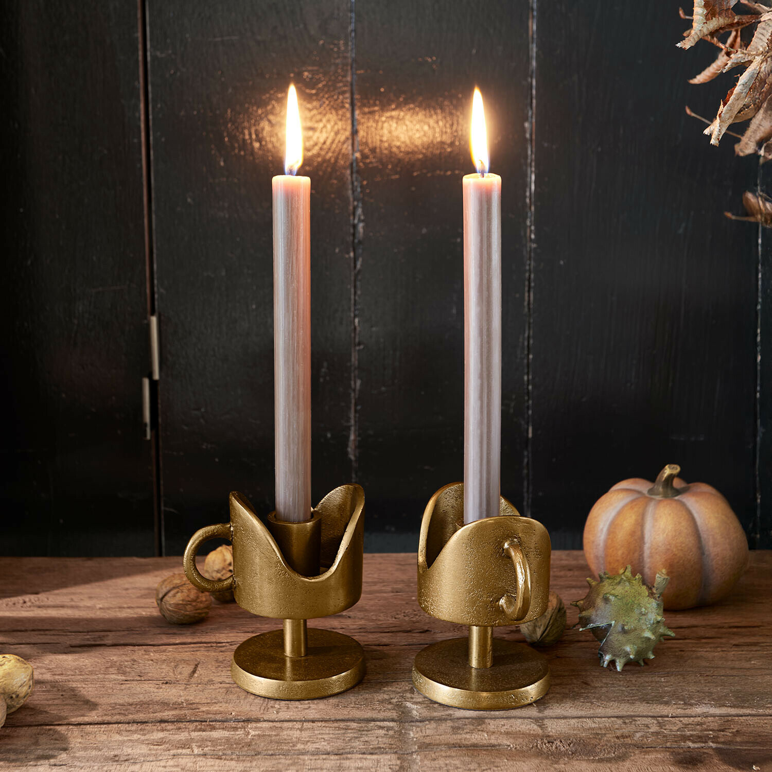 Lot de 2 bougeoirs Mirodella Paire de bougeoirs dorés en métal avec poignées et bougies beige sur table en bois avec décorations d'automne