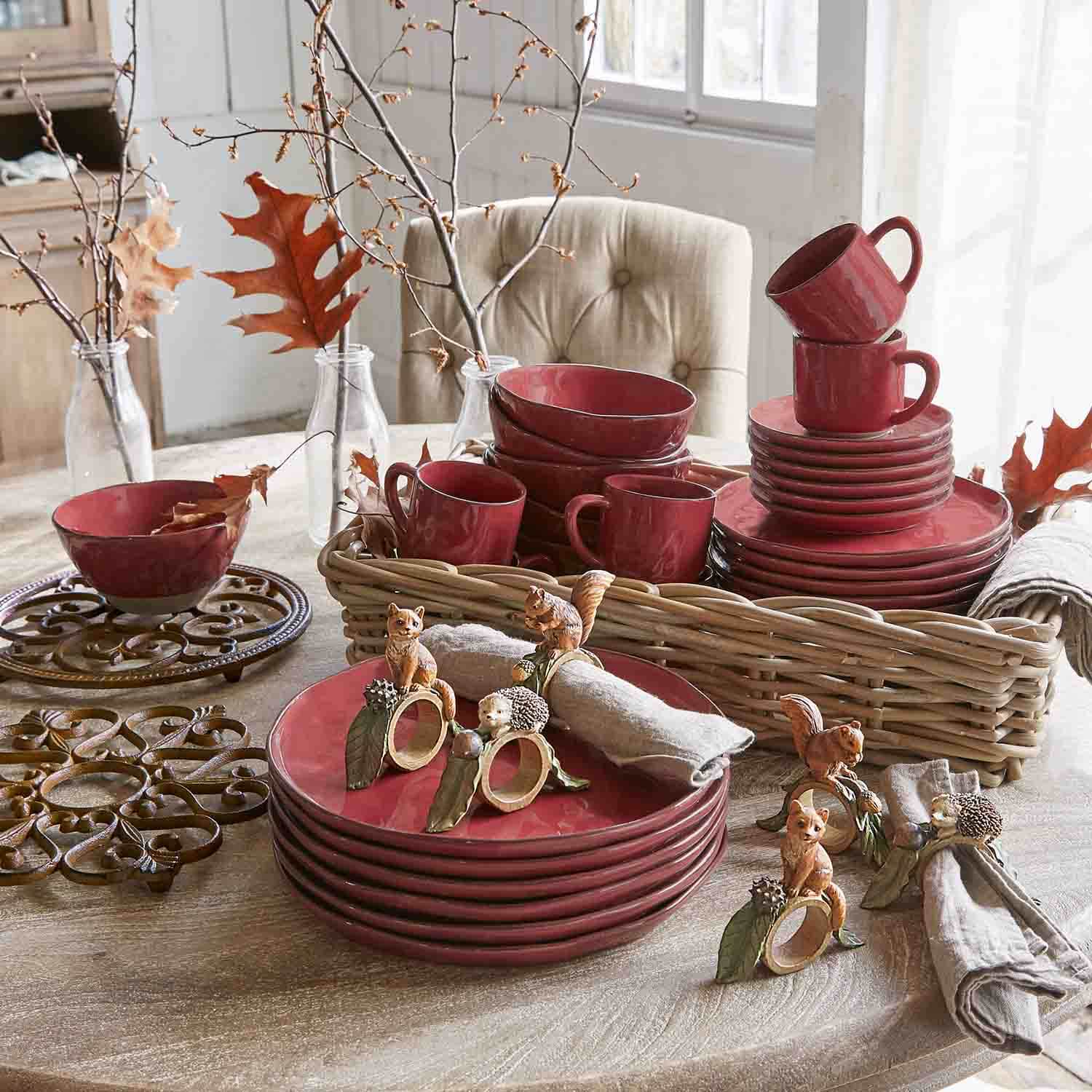 Service de table en céramique rouge avec tasses et assiettes sur table en bois décorée d'éléments d'automne