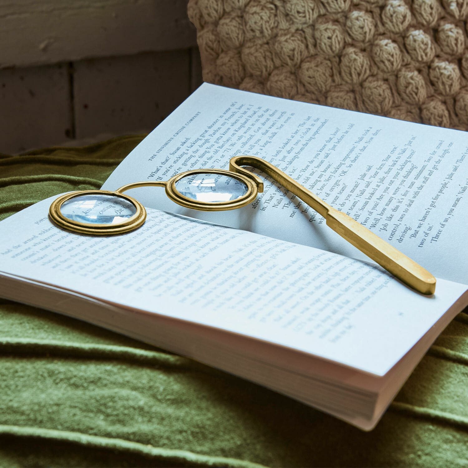 Loupe Robert Lunettes de lecture dorées à verres ronds posées sur un livre ouvert sur tissu vert
