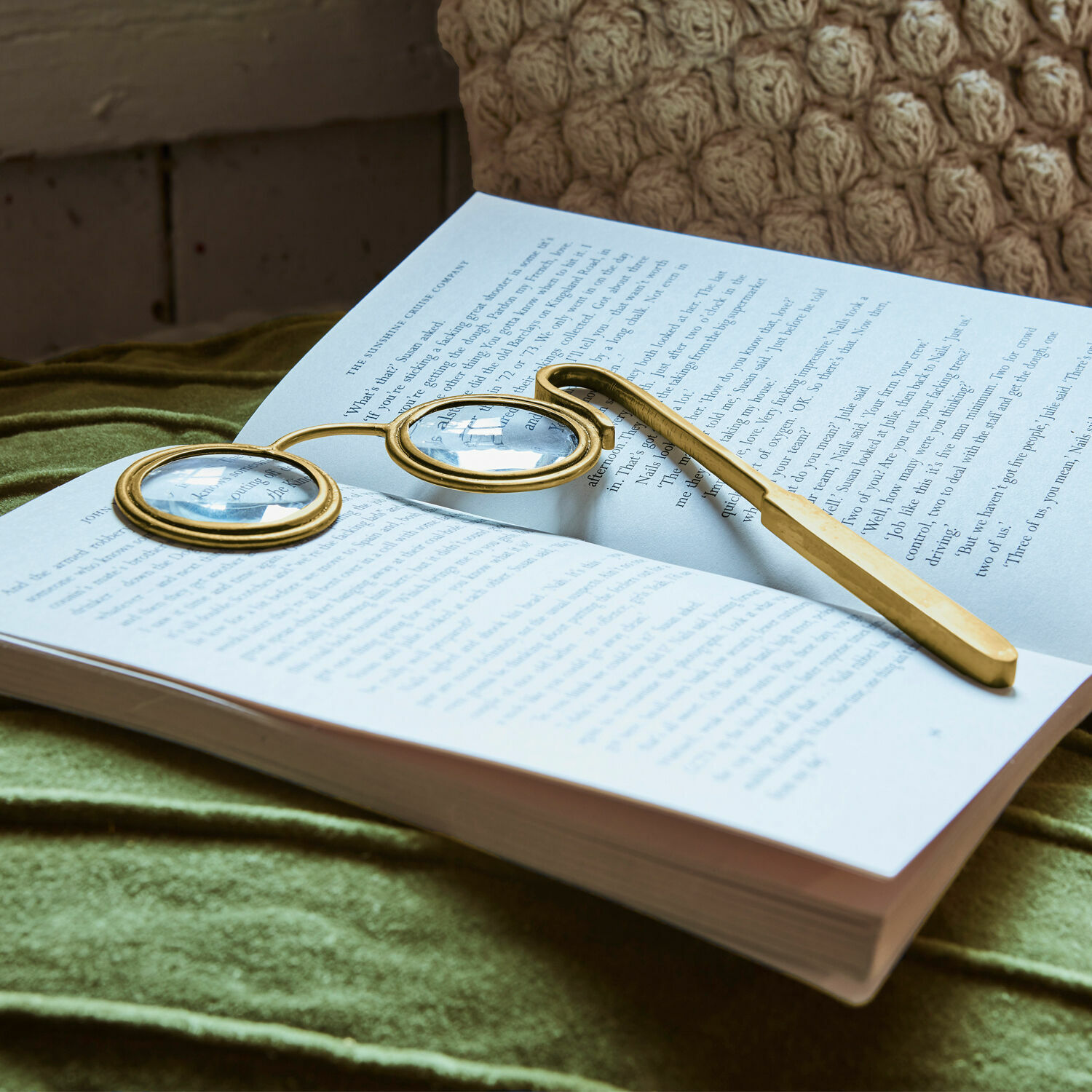 Loupe Robert Lunettes de lecture dorées à verres ronds posées sur un livre ouvert sur tissu vert