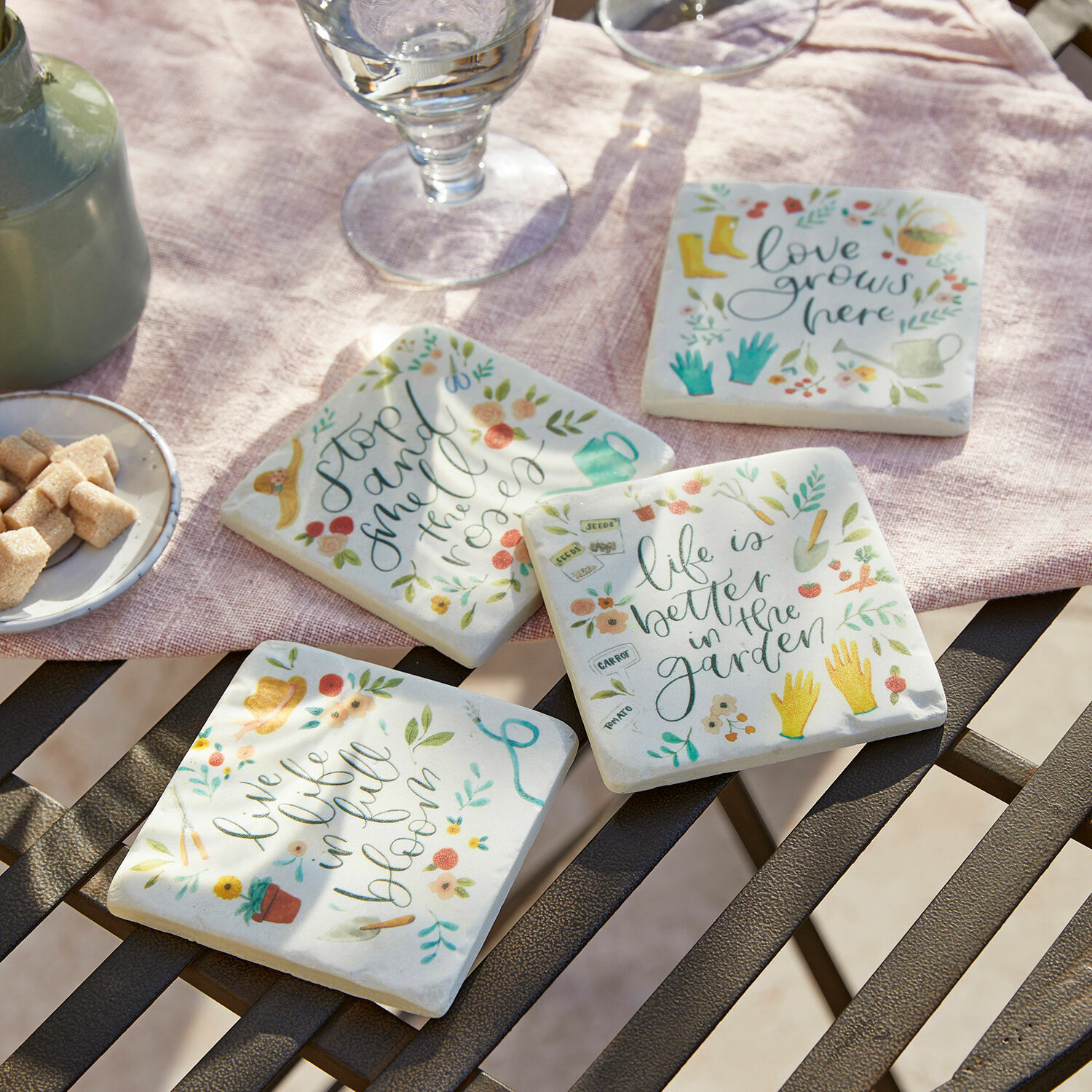 Lot de 4 dessous de verres Happy Ensemble de quatre dessous de verre en céramique avec motifs de jardin colorés et inscriptions sur fond clair