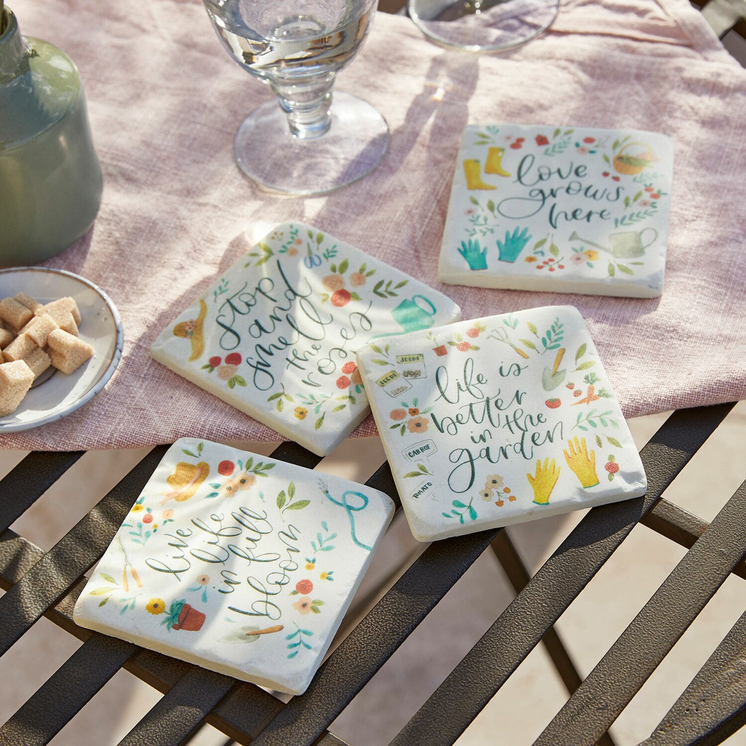 Lot de 4 dessous de verres Happy Ensemble de quatre dessous de verre en céramique avec motifs de jardin colorés et inscriptions sur fond clair