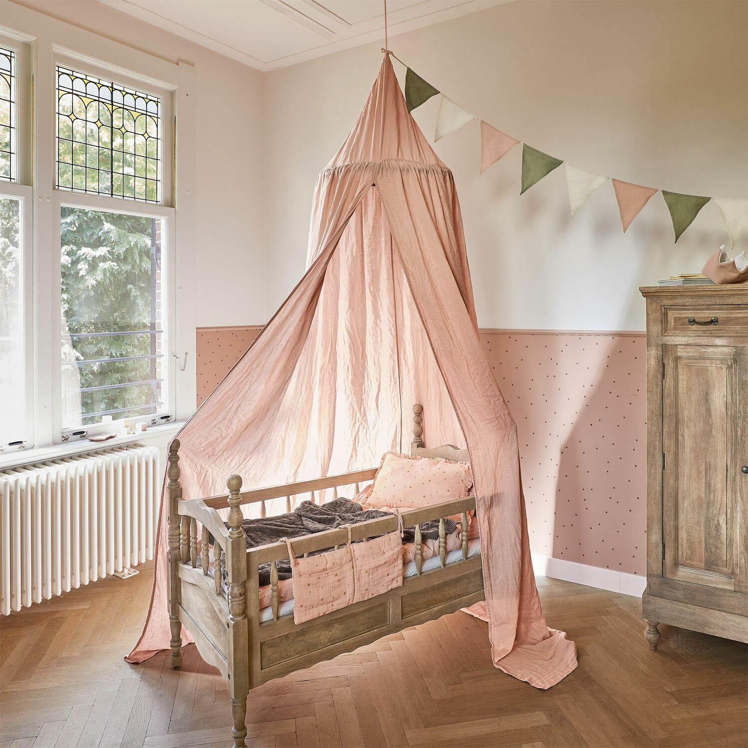 Ciel de lit Lisonne Lit enfant en bois avec baldaquin rose et coussins décoratifs dans une chambre d'enfant lumineuse