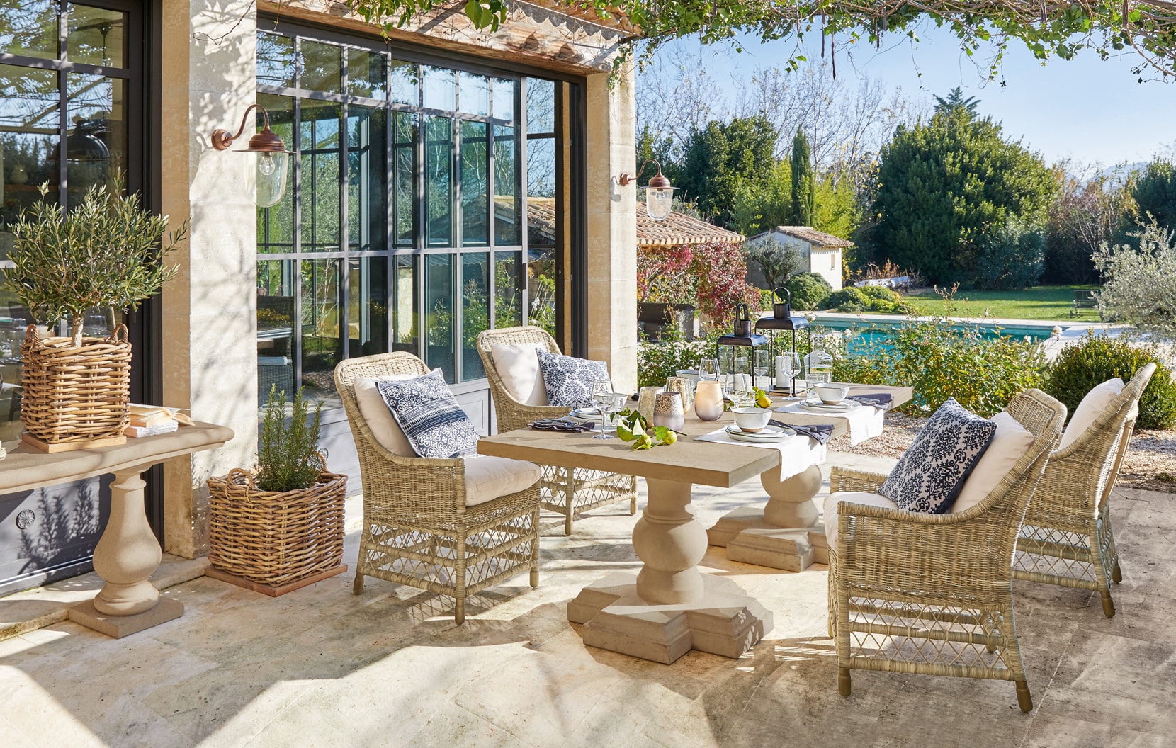 Terrasse accueillante avec mobilier en rotin et table en pierre dans un style méditerranéen avec vue sur la piscine