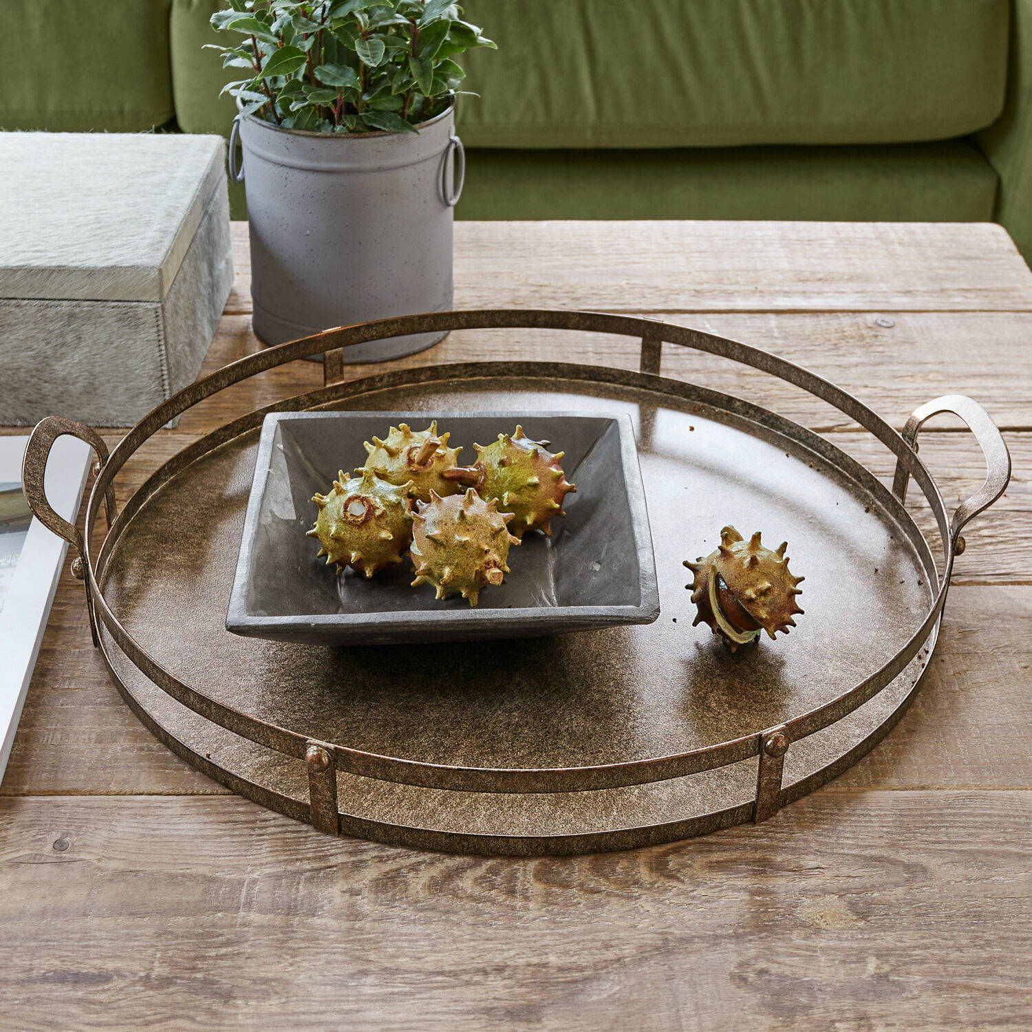 Plateau Aquivar Plateau rond en métal couleur laiton sur table en bois avec bol en céramique et marrons décoratifs