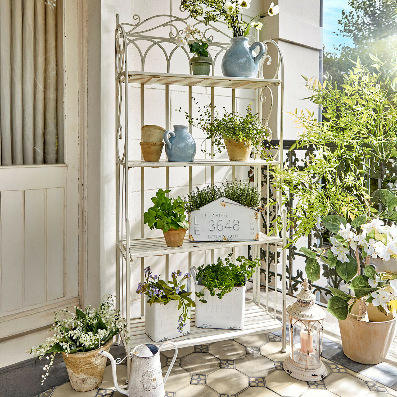 Étagère en métal blanc avec plantes en pot et décorations sur un balcon lumineux