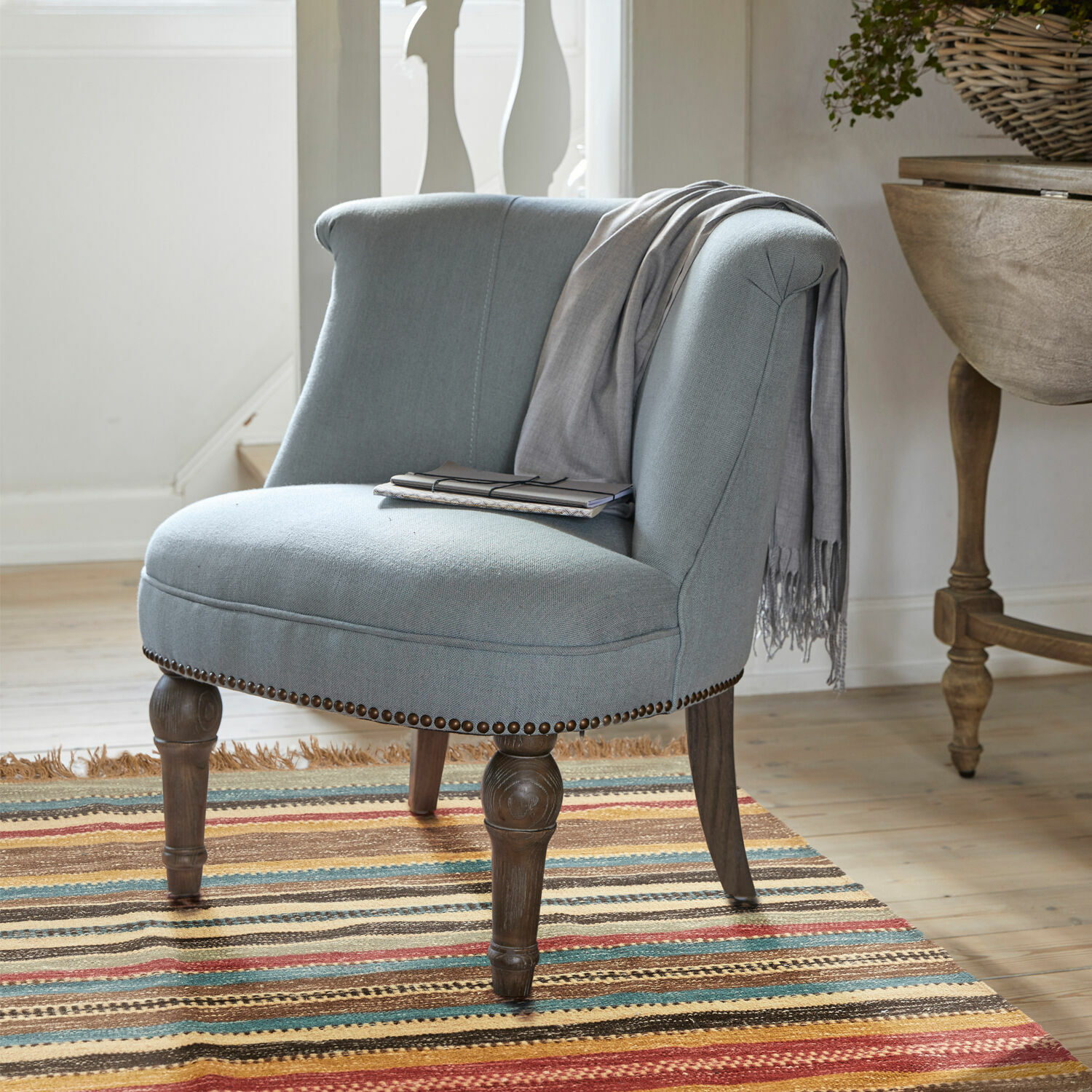 Fauteuil Francet Fauteuil gris en tissu avec pieds en bois sur tapis coloré dans un intérieur lumineux