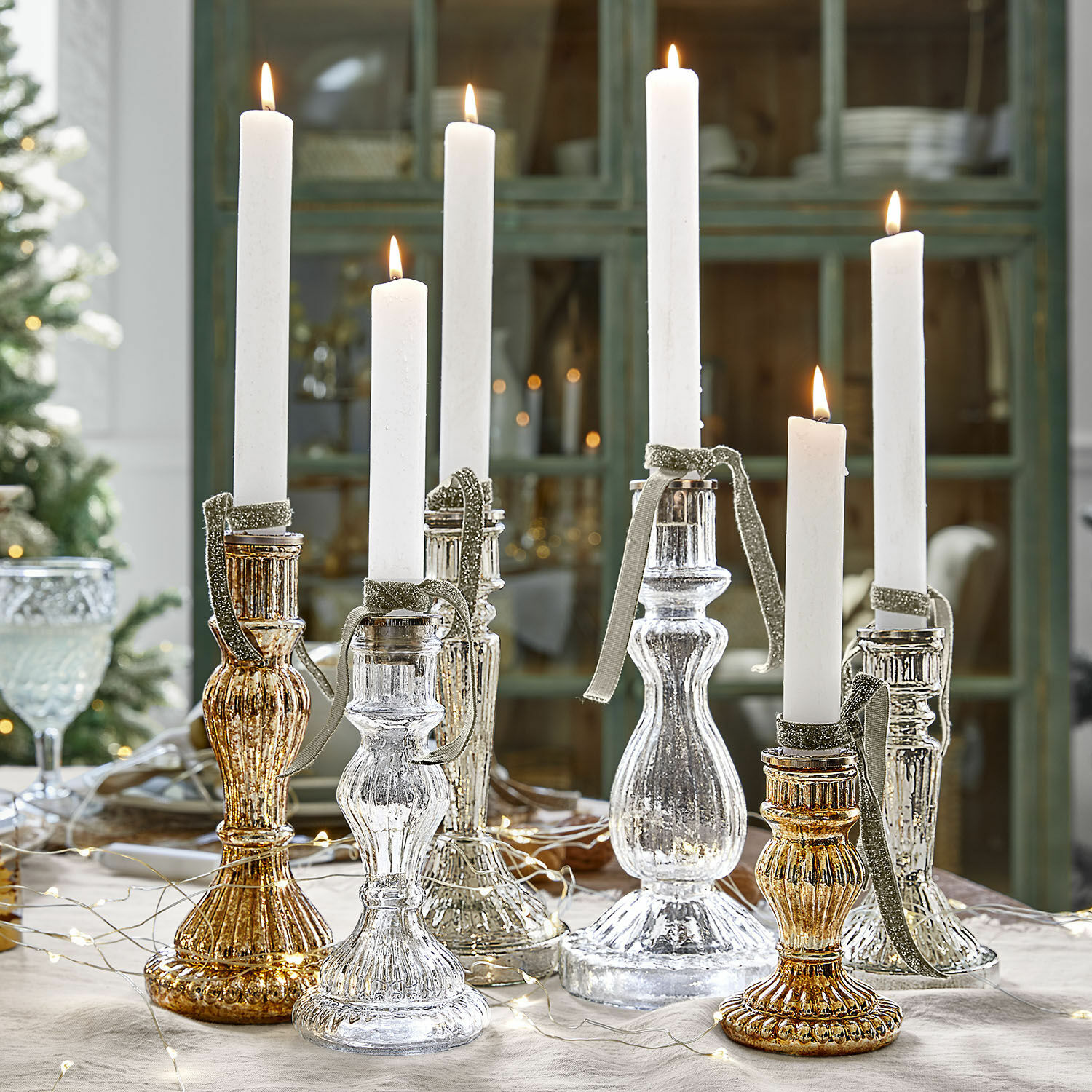 Lot de 6 bougeoirs Quirène Ensemble de chandeliers en verre doré et argenté avec bougies blanches sur une table décorée pour Noël