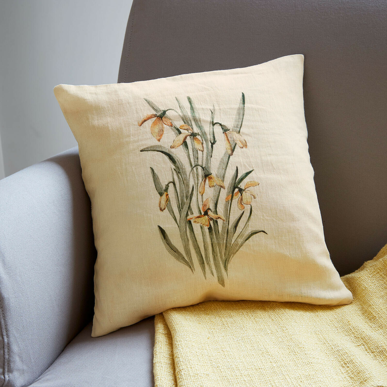 Housse de coussin Lozere Coussin en lin beige avec motif floral jaune sur canapé gris et couverture jaune